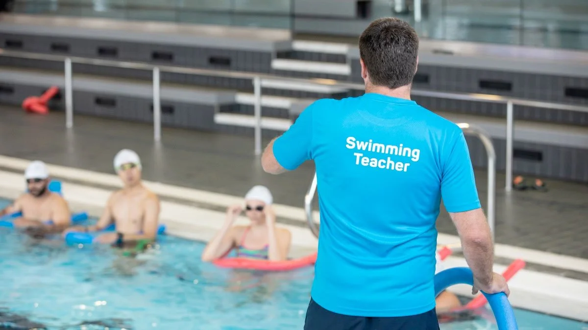 male swim teacher teaching a group sesson