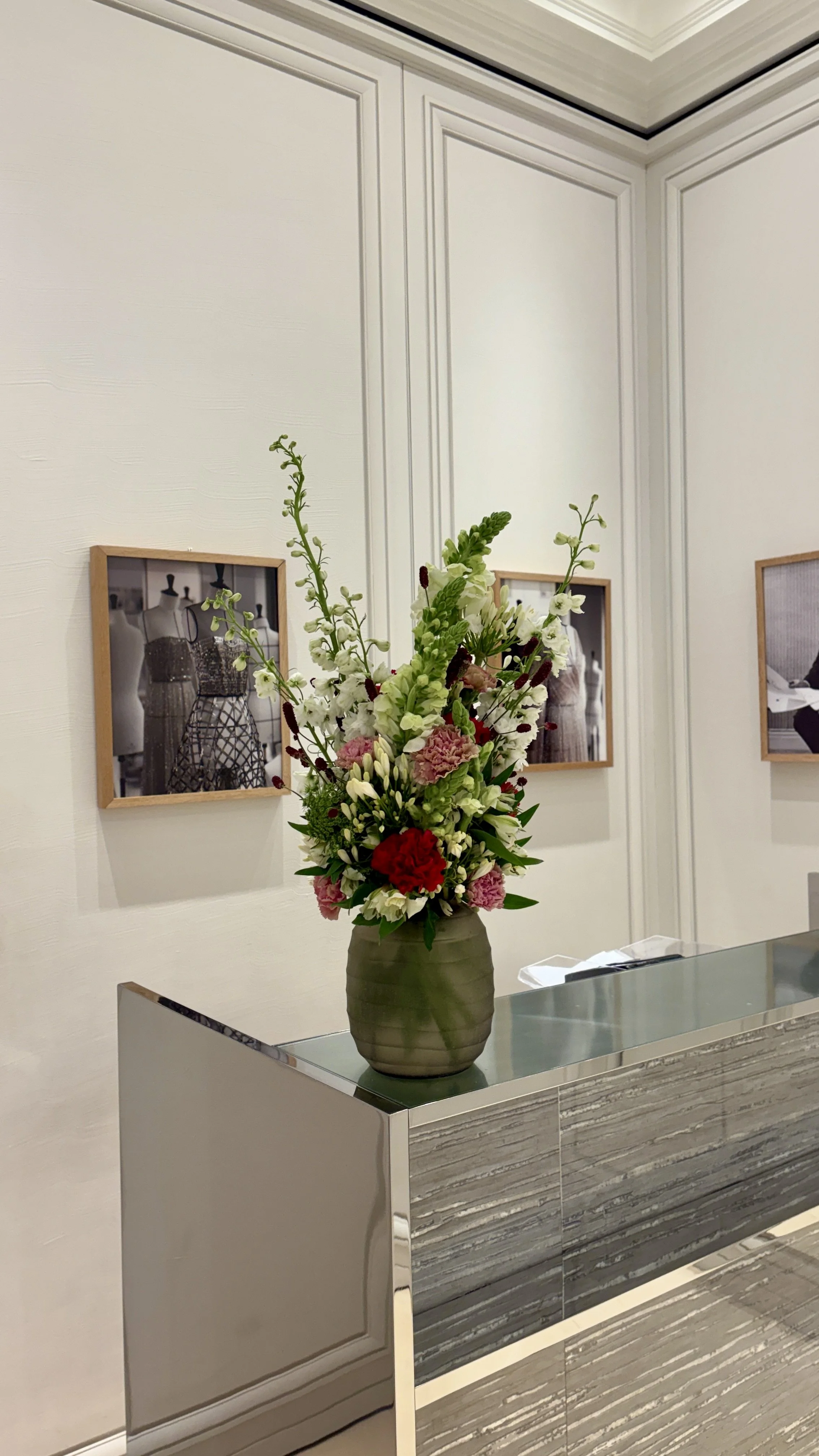 Contemporary floral composition on a luxury reception desk in a Barcelona flagship store, featuring seasonal blooms and refined design