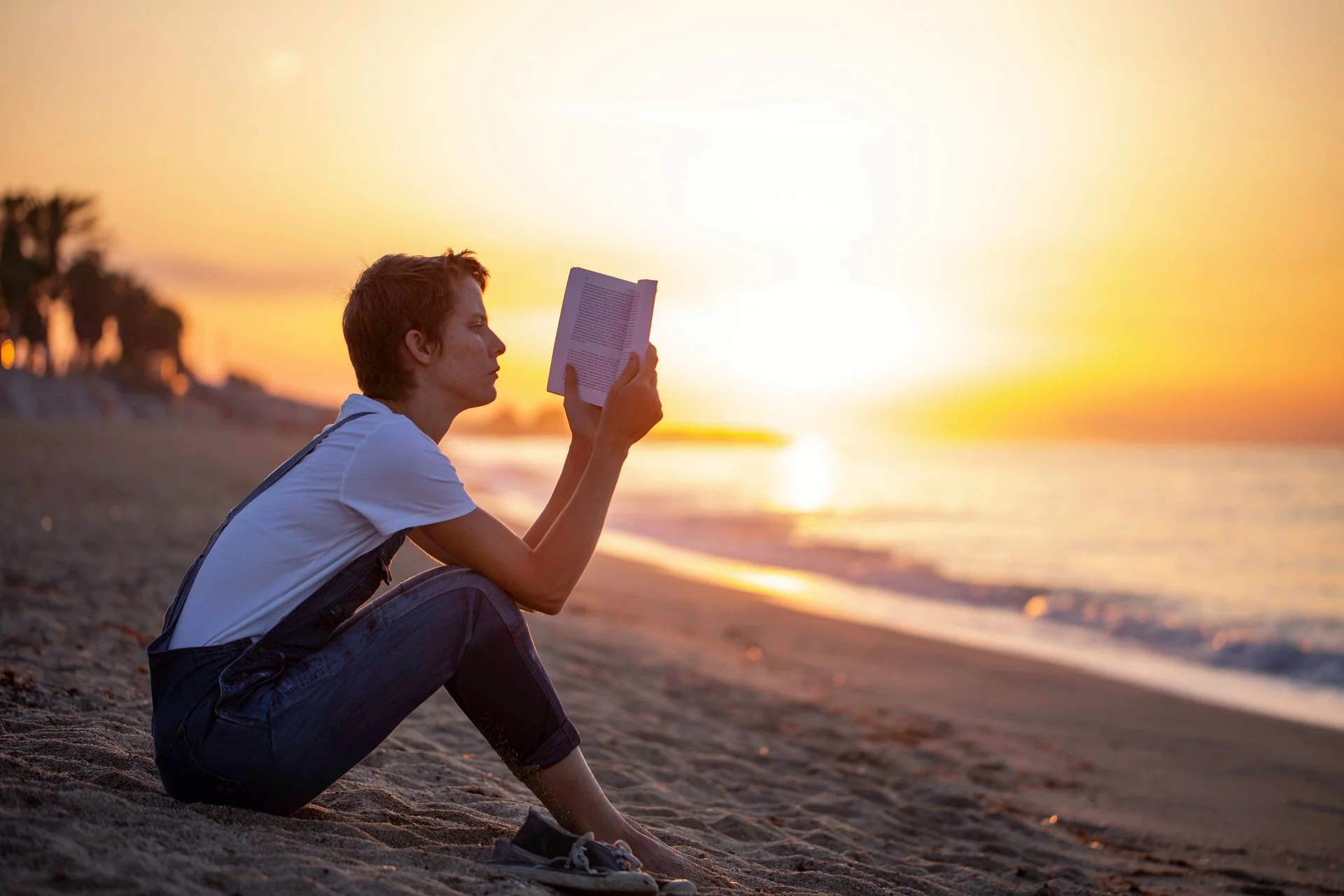 Floral designer Margaux Bastid reading at sunrise on the Barcelona beach, finding inspiration for international floral events