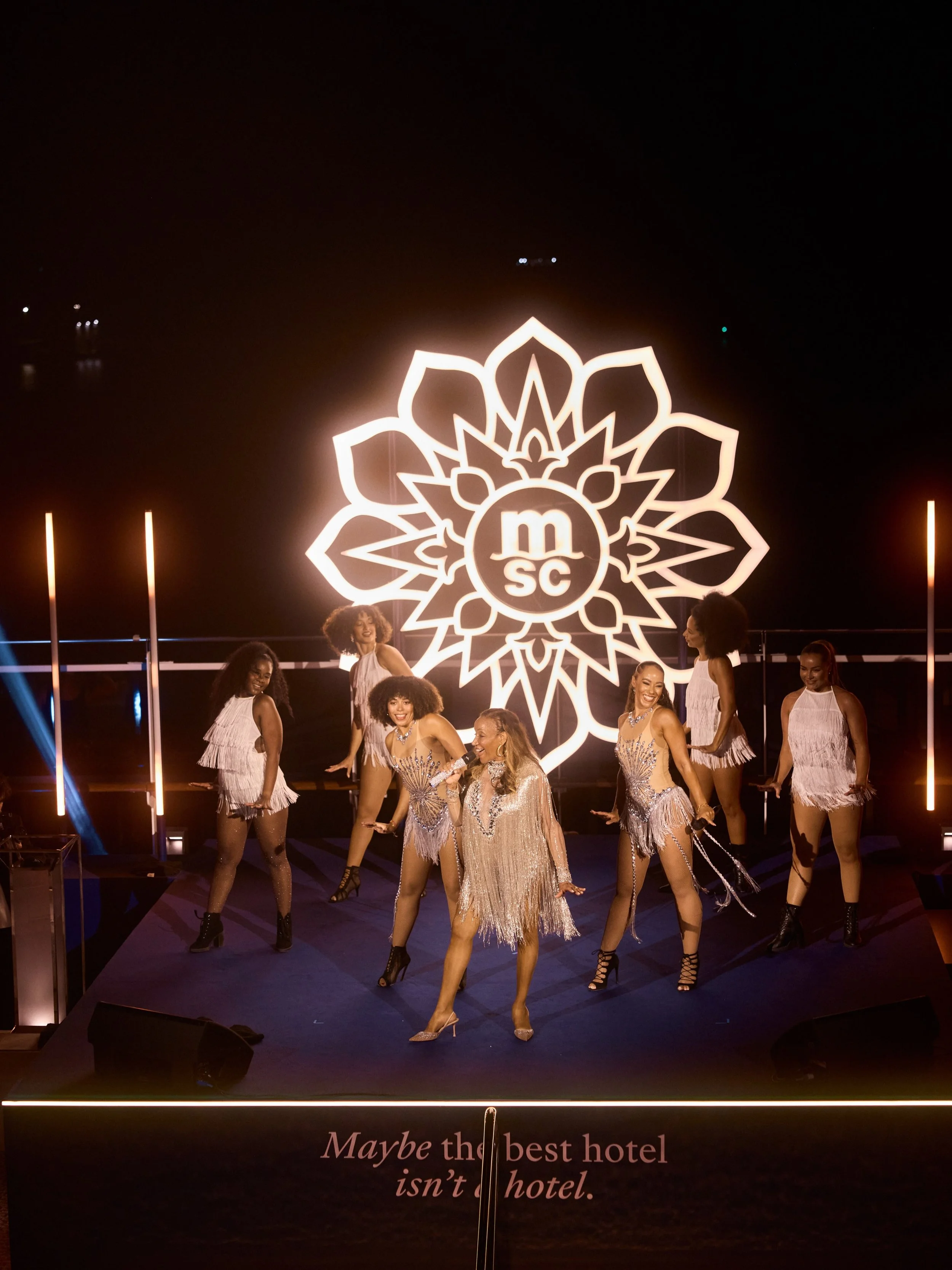 Live performers on stage with Mosaic's illuminated botanical backdrop