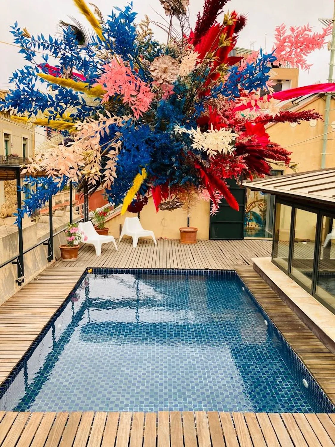 Suspended floral installation by Mosaic above a rooftop pool in Barcelona, made with hand-painted dried flowers for luxury celebrations