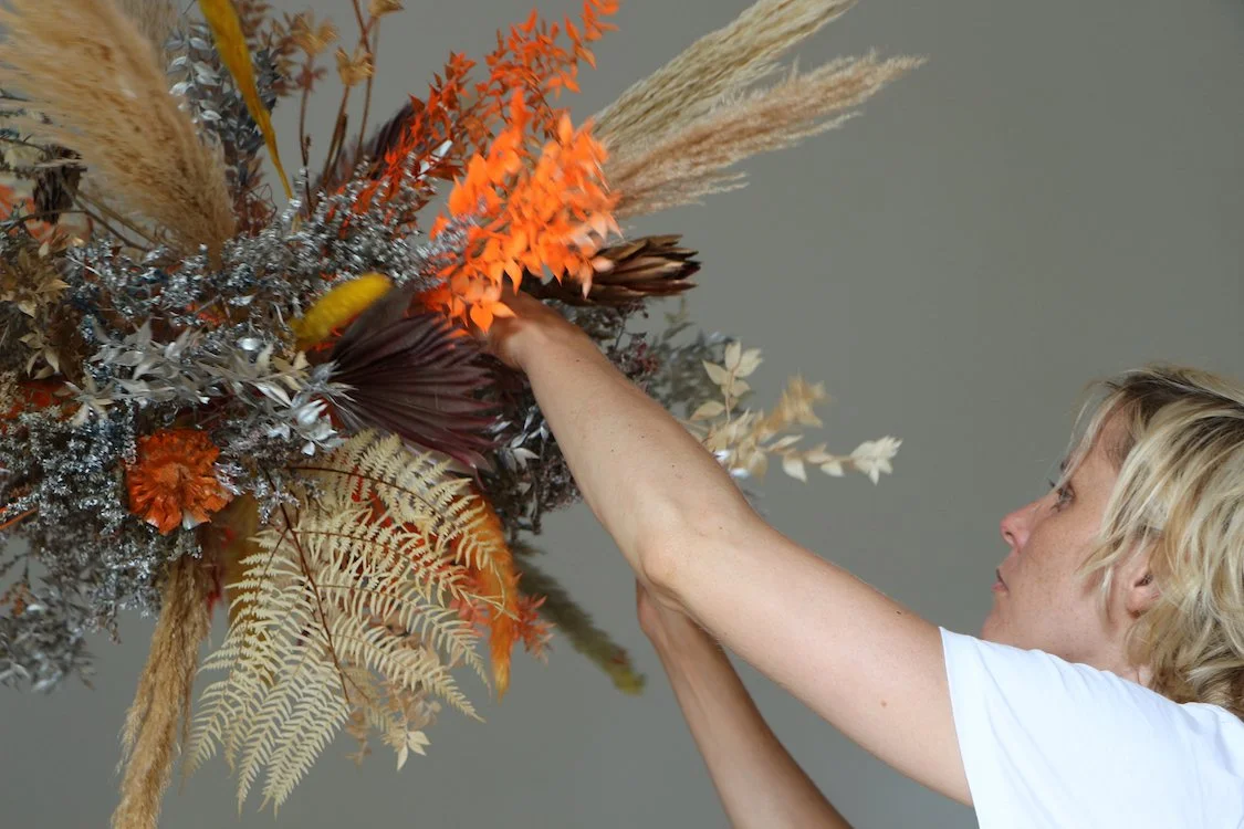 Floral artist Margaux of Mosaic creating a ceiling floral sculpture in warm tones for a high-end Barcelona event