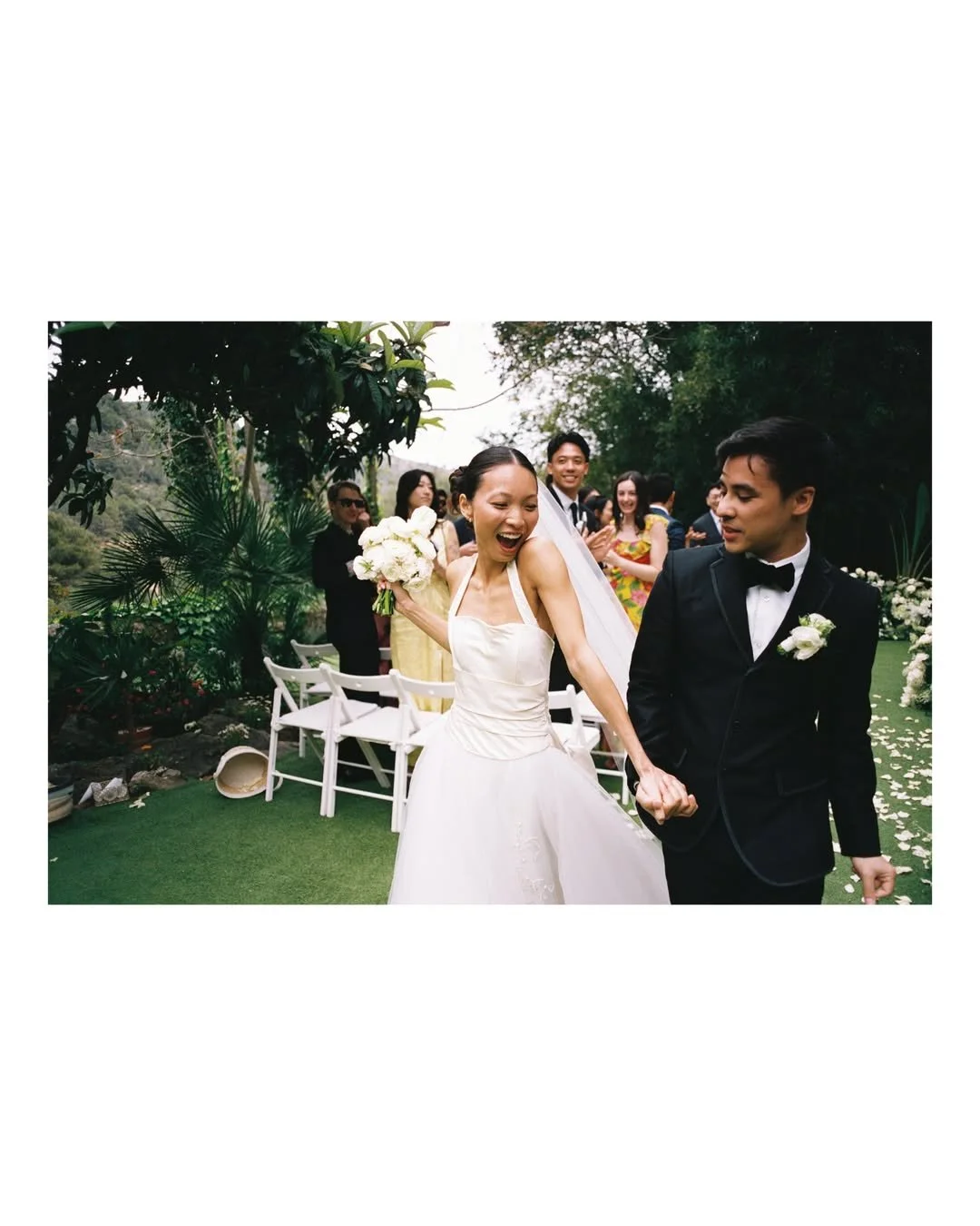 Newlyweds Christie and Andrew leaving the ceremony carrying a bespoke bridal bouquet surrounded by elegant floral décor at Villa Almanita