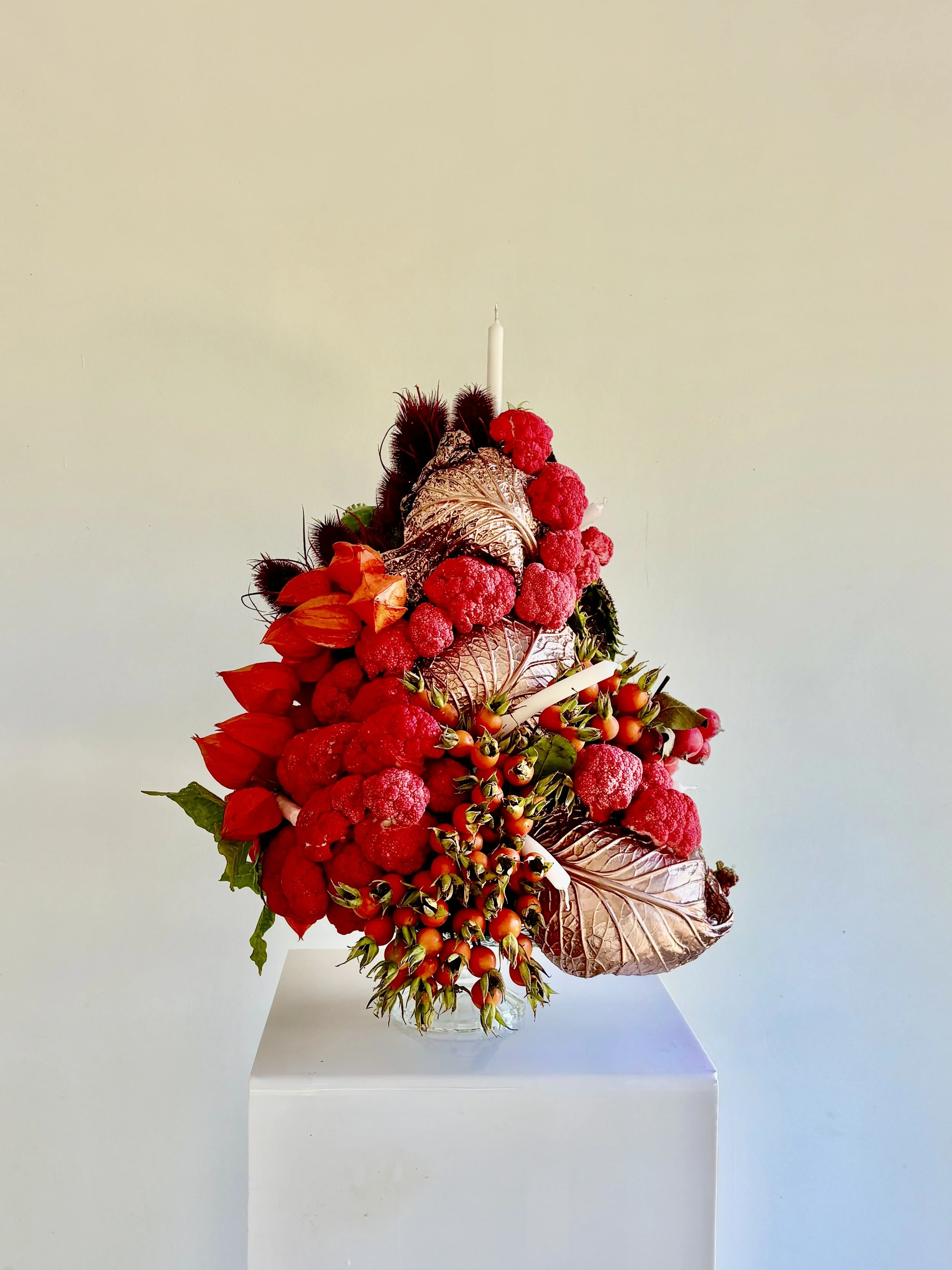 An original floral composition created by Mosaic for Blanca Miró’s birthday as a gift from LA VESTE, featuring layered flowers, foliage, seasonal produce and candles in a sculptural arrangement