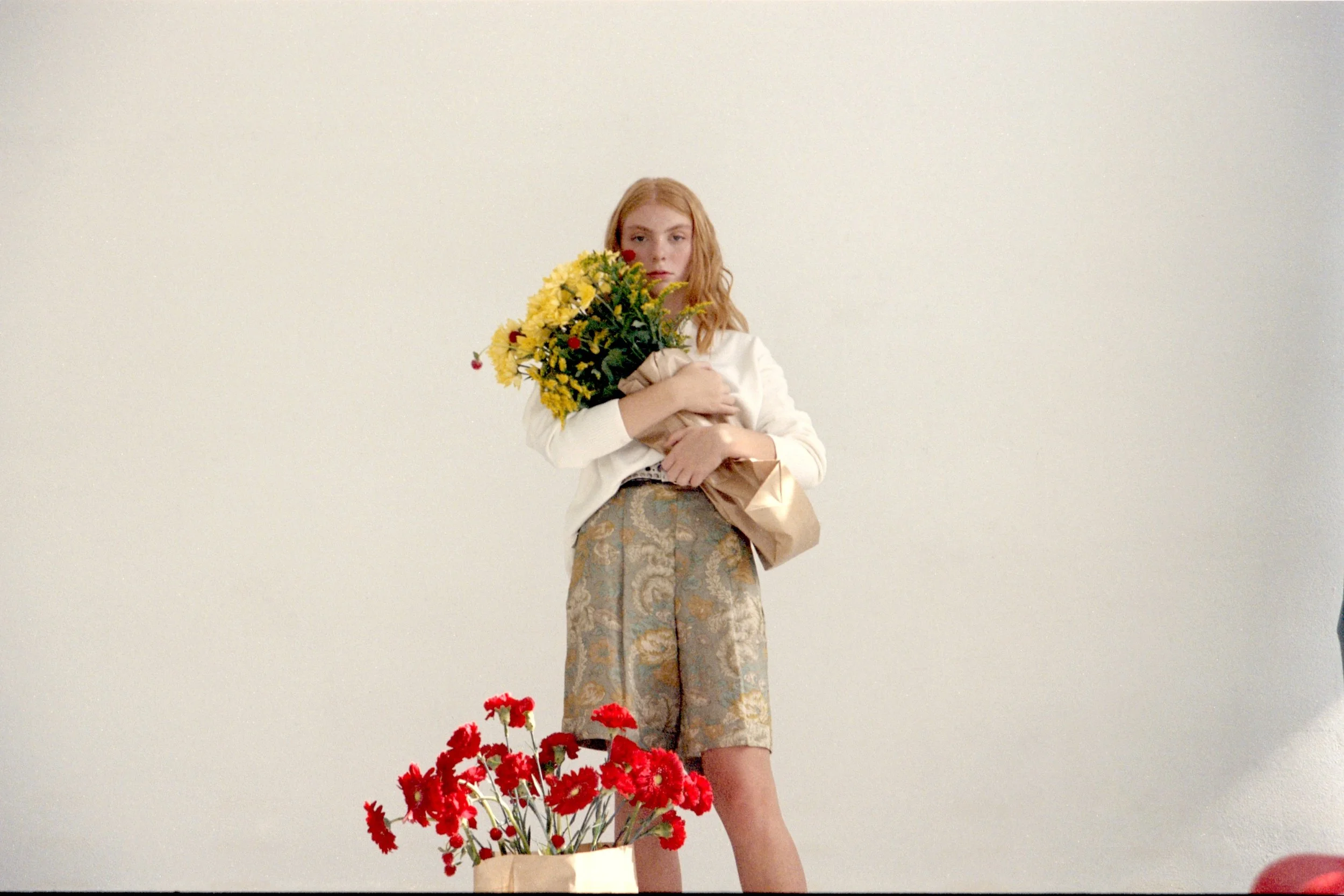 Lifestyle editorial scene with ginger-haired model holding red and yellow flowers for a Mosaic creative project in Barcelona