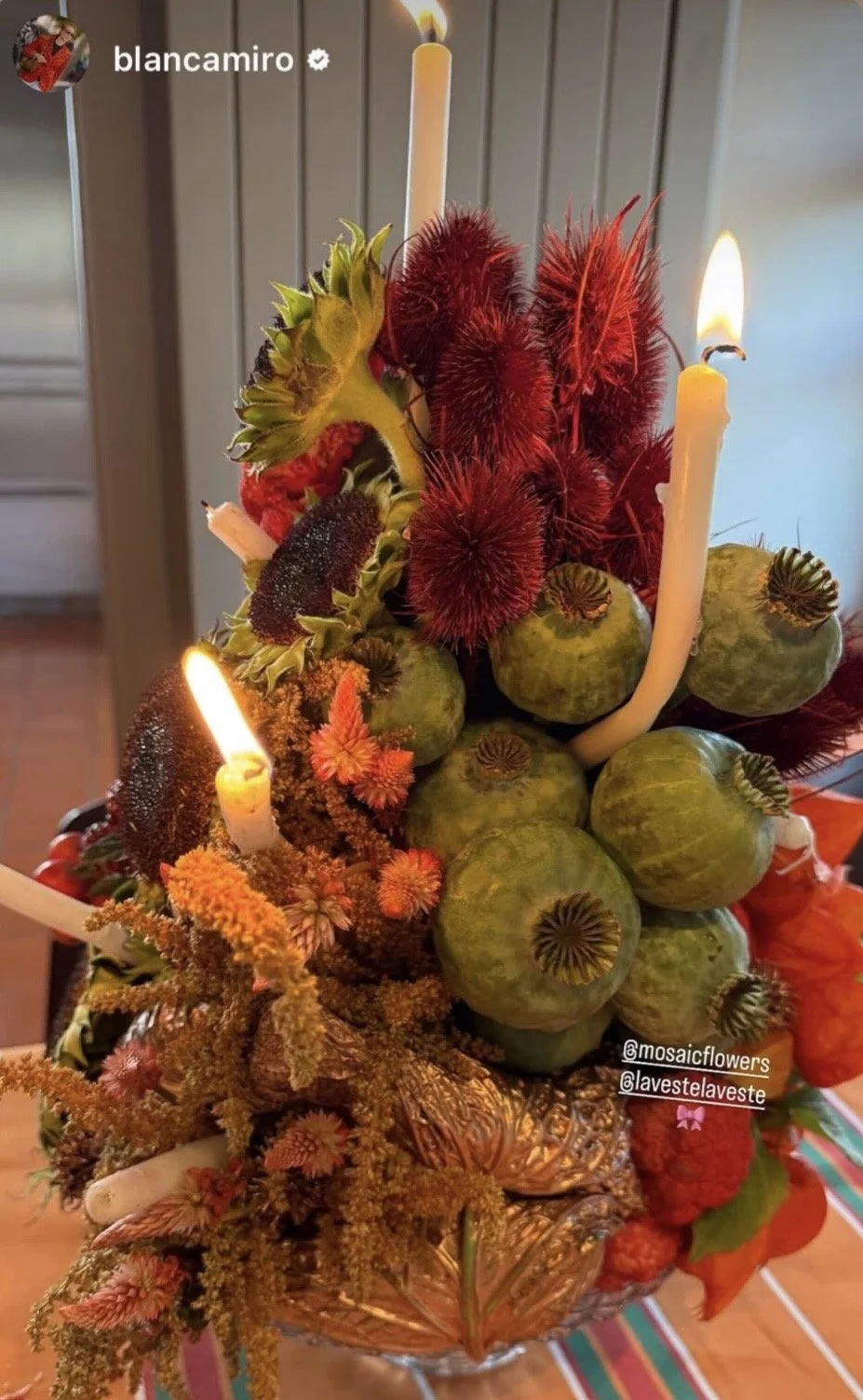 A distinctive floral cake designed by Mosaic for Blanca Miró’s birthday, gifted by LA VESTE and composed entirely as a creative botanical artwork with flowers, produce, foliage and candles