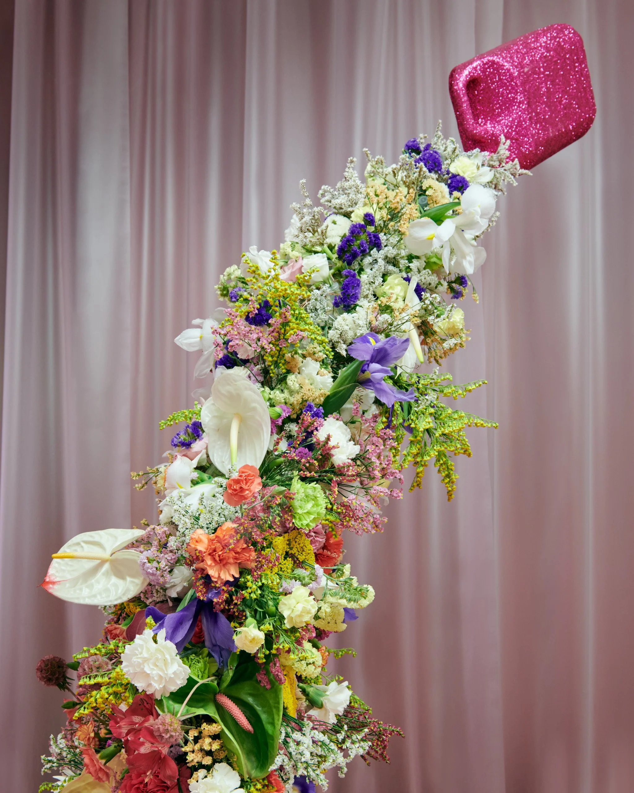 Colorful flowers cascading from Mosaic’s sculptural pink bottle in The Bathroom exhibition