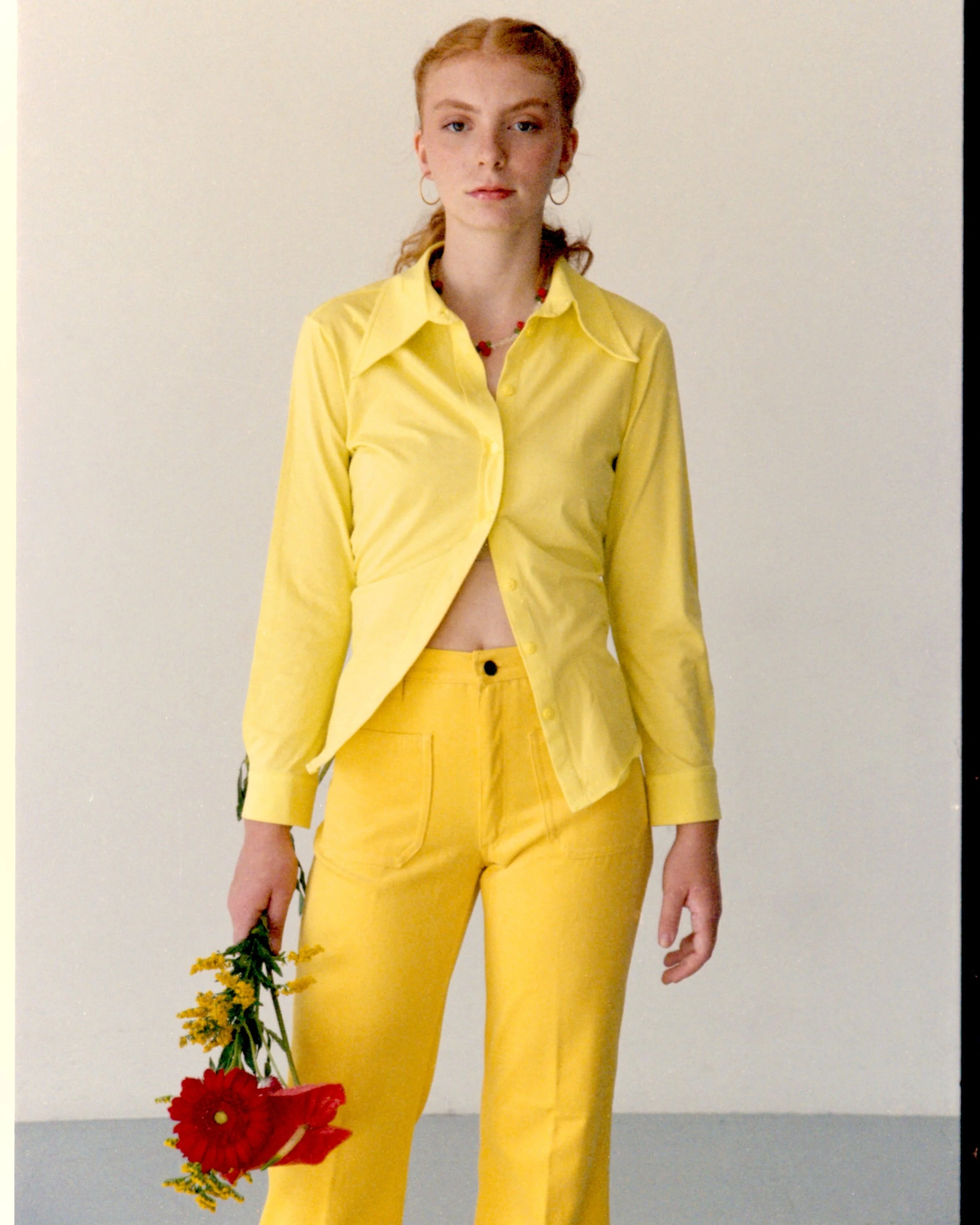 Model wearing a bright yellow outfit holding flowers during a creative editorial photoshoot in Barcelona by Mosaic