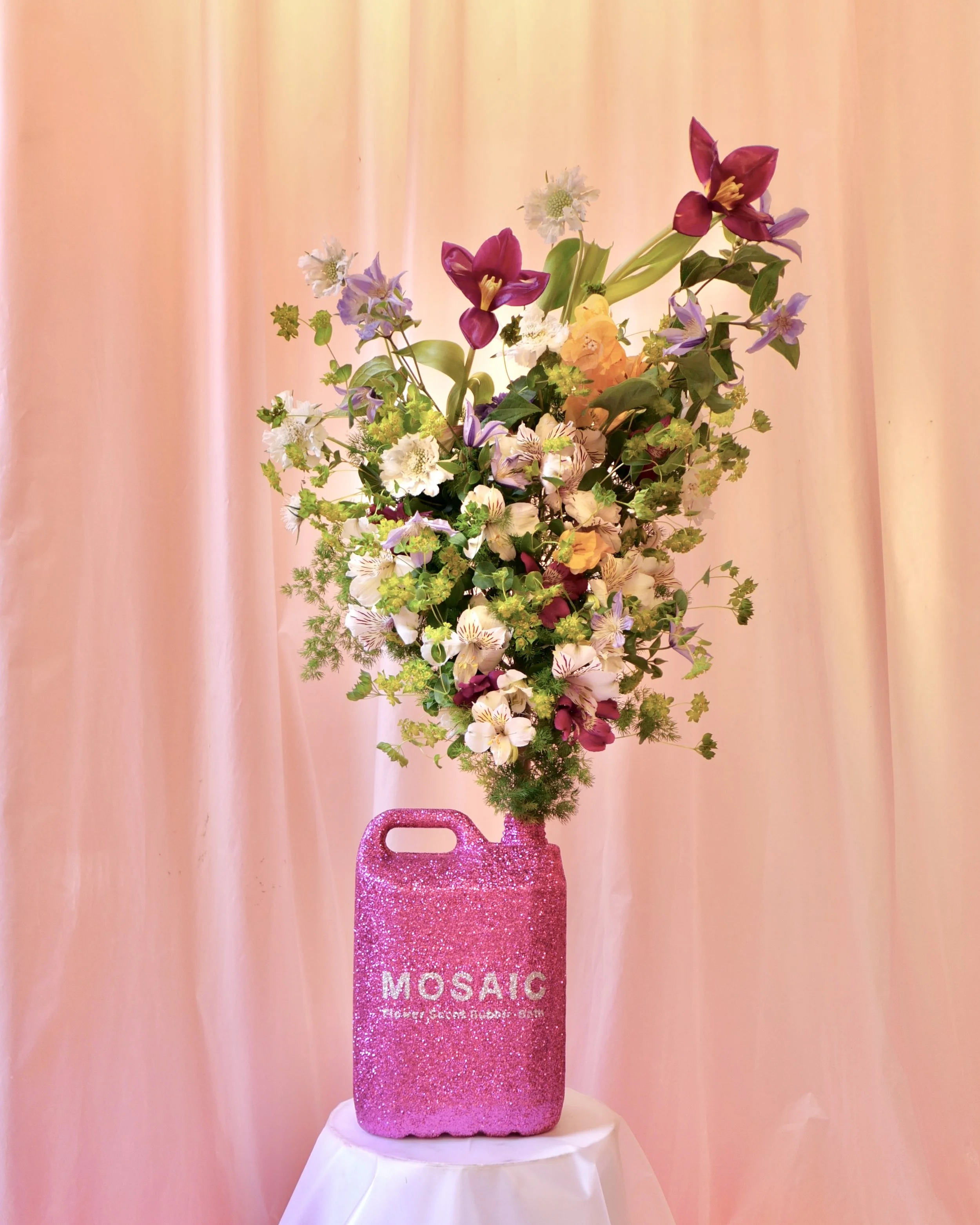 Iconic Mosaic pink bottle filled with flowers, designed as part of The Bathroom exhibition exploring floral sculpture