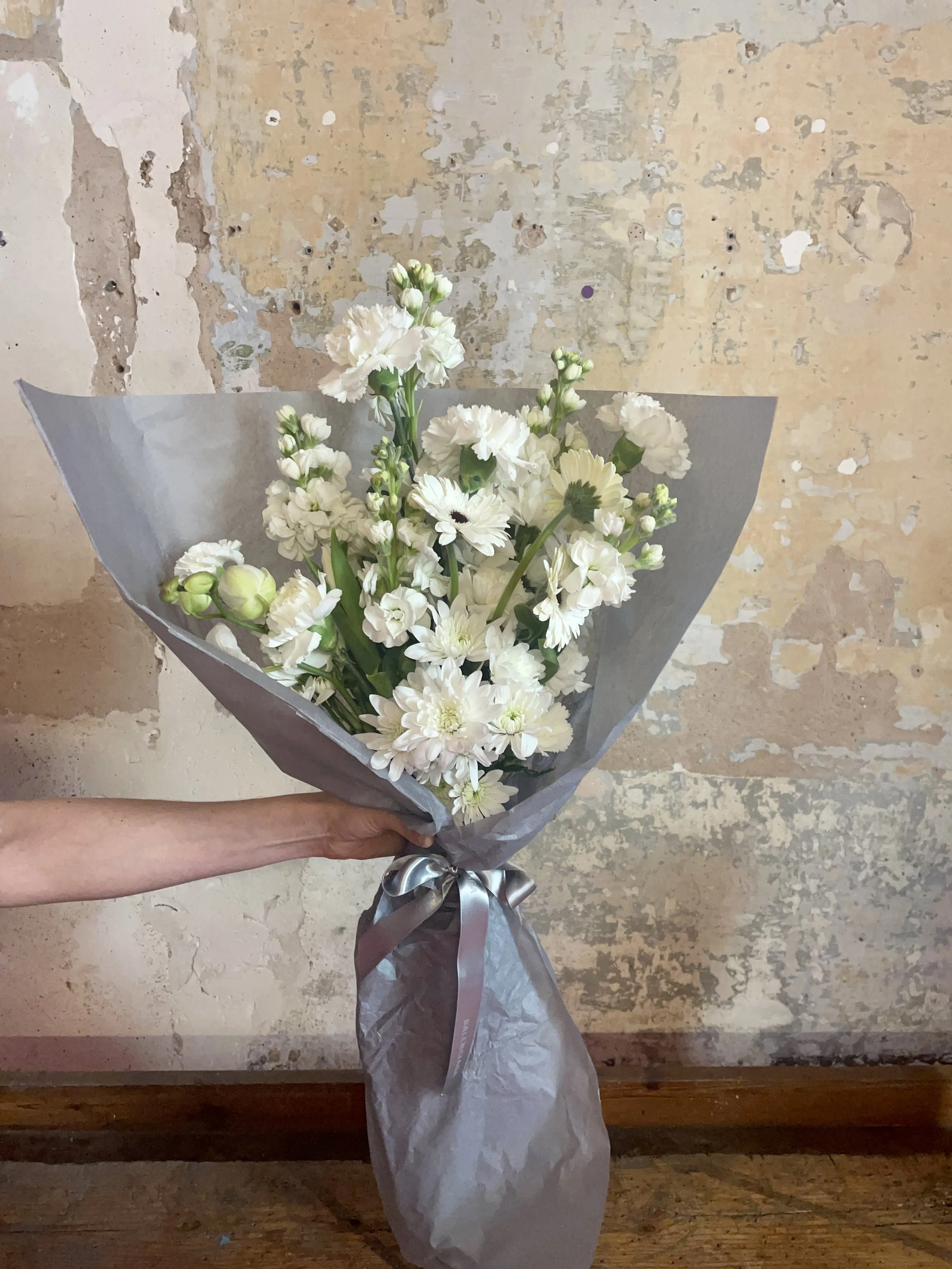 Handcrafted white bouquet wrapped in elegant grey paper, designed by Mosaic for Balenciaga’s client gifting in Barcelona