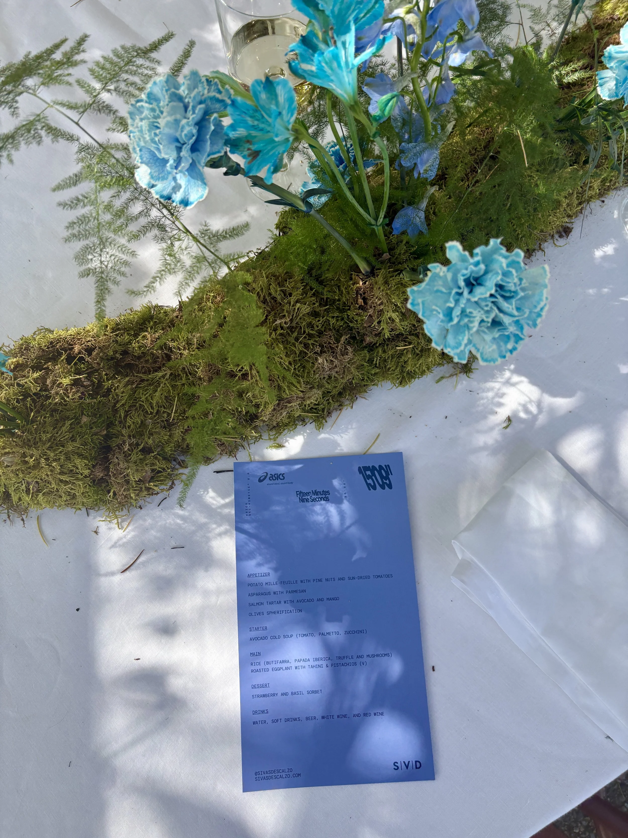 Elegant place setting featuring the bespoke moss runner and blue floral arrangement created for the ASICS luxury event organized by Gabsfood near Barcelona