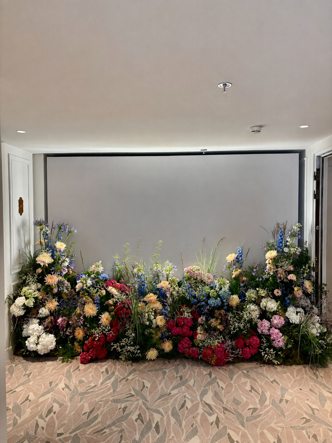 Wide view of an abundant floral backdrop by Mosaic Flowers for a Ritz-Carlton suite in Cannes, designed for an international luxury brand with colourful seasonal flowers and immersive floral styling