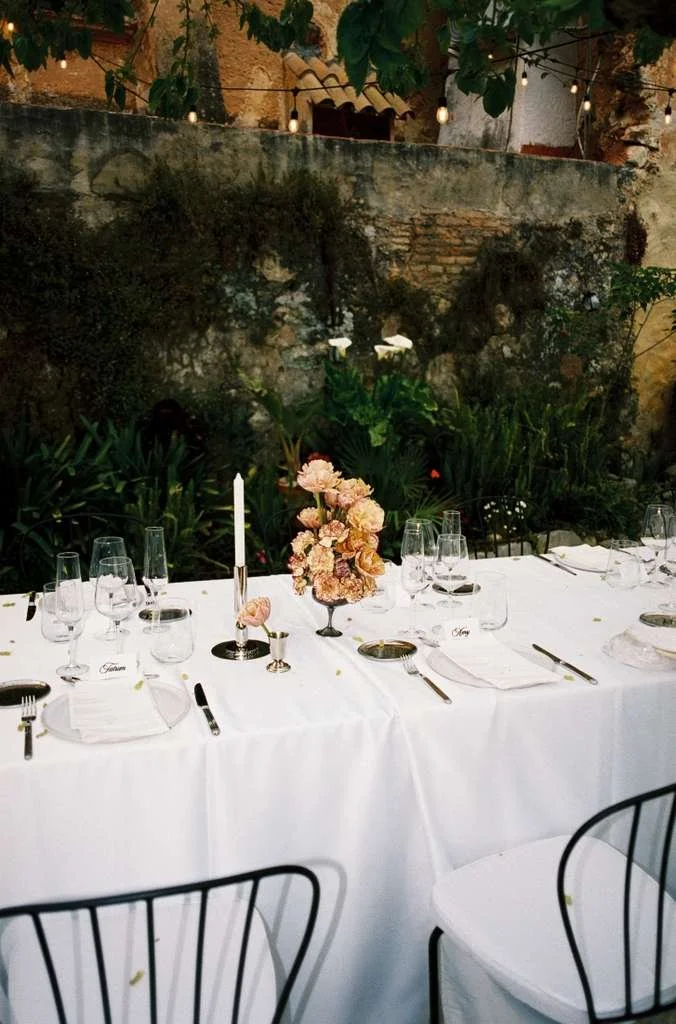 Refined round table floral centrepiece combining sculptural forms and seasonal flowers for a luxury wedding reception