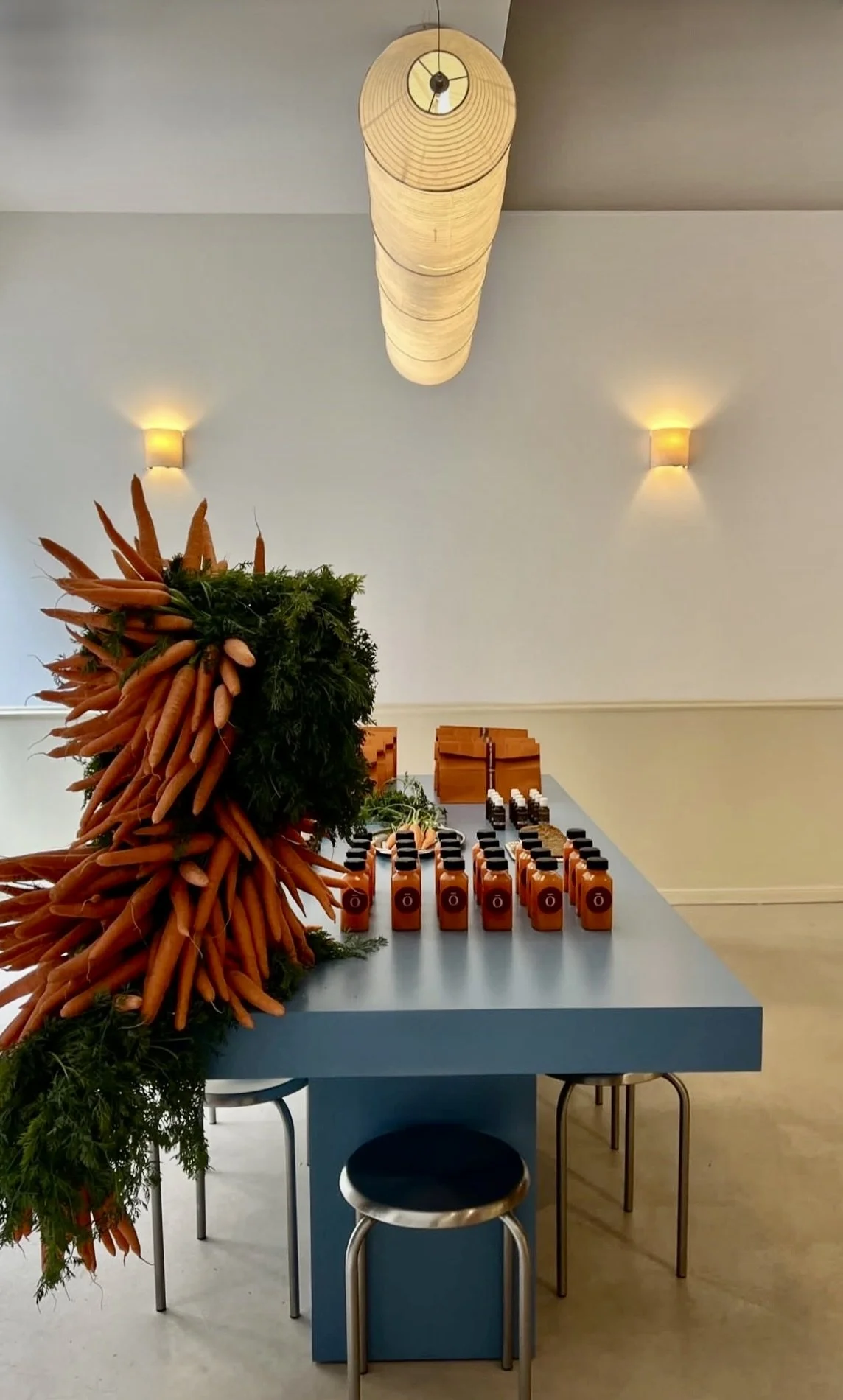 Unique floral scenography by Mosaic for Pranarôm, featuring a dramatic carrot sculpture surrounded by fresh greenery and designed as an artistic focal point for the cosmetic brand’s press event