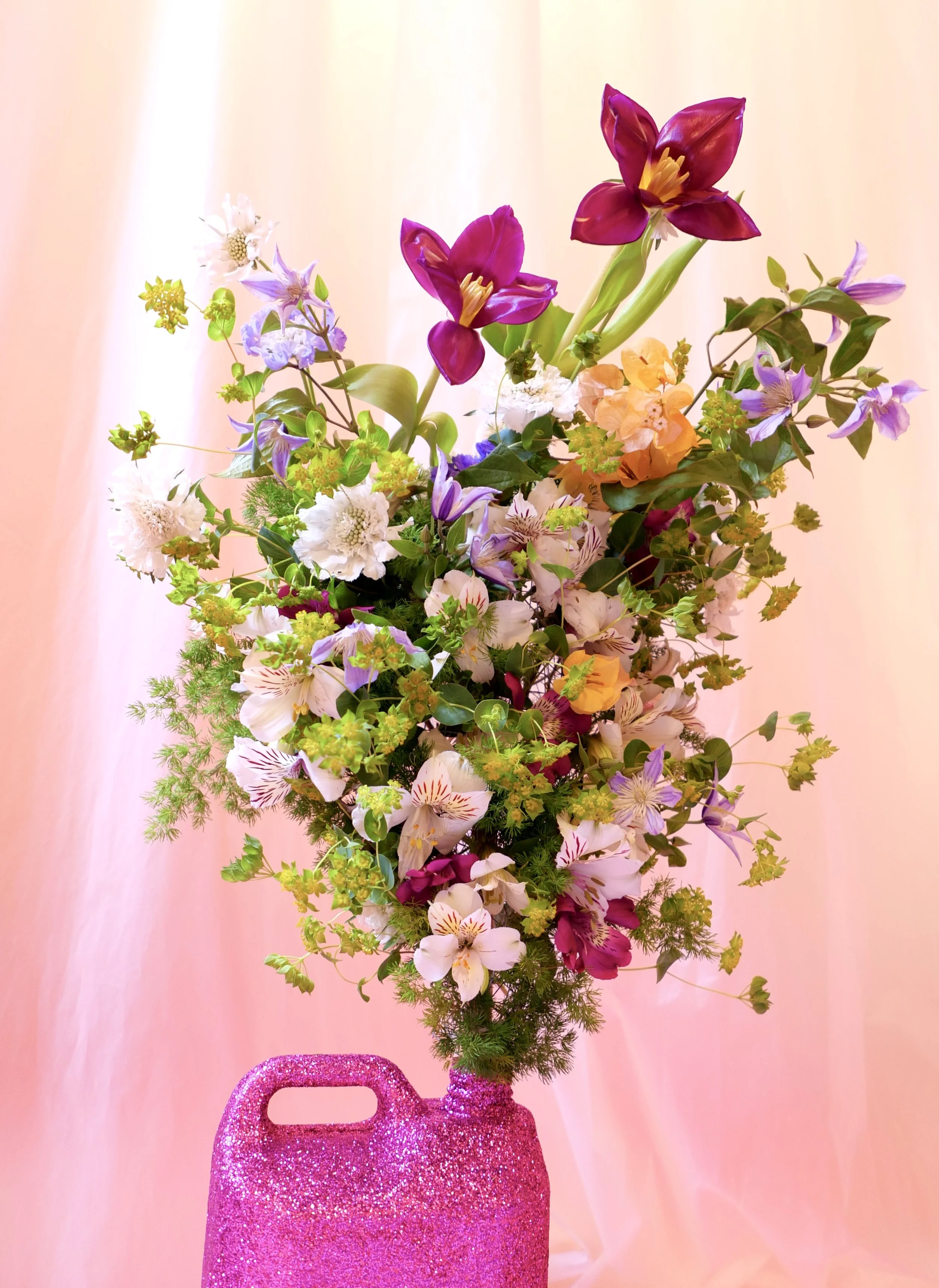 Explosion of colorful flowers arranged in Mosaic’s iconic pink bottle, created for The Bathroom exhibition