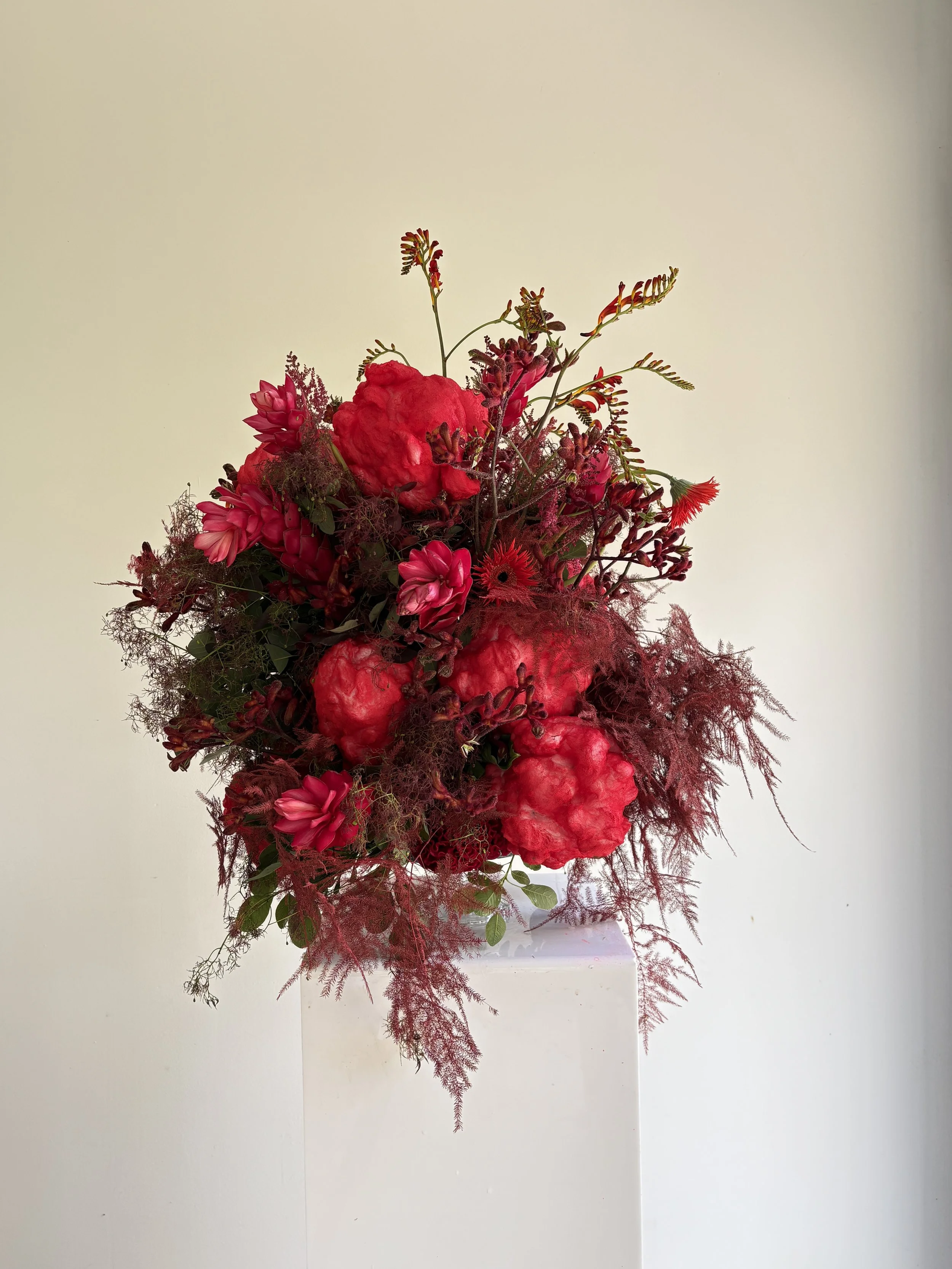 Sculptural luxury floral composition in vibrant crimson tones created for Blanca Miró by Mosaic Flowers, celebrating the birth of her daughter with bold seasonal blooms and artistic botanical design