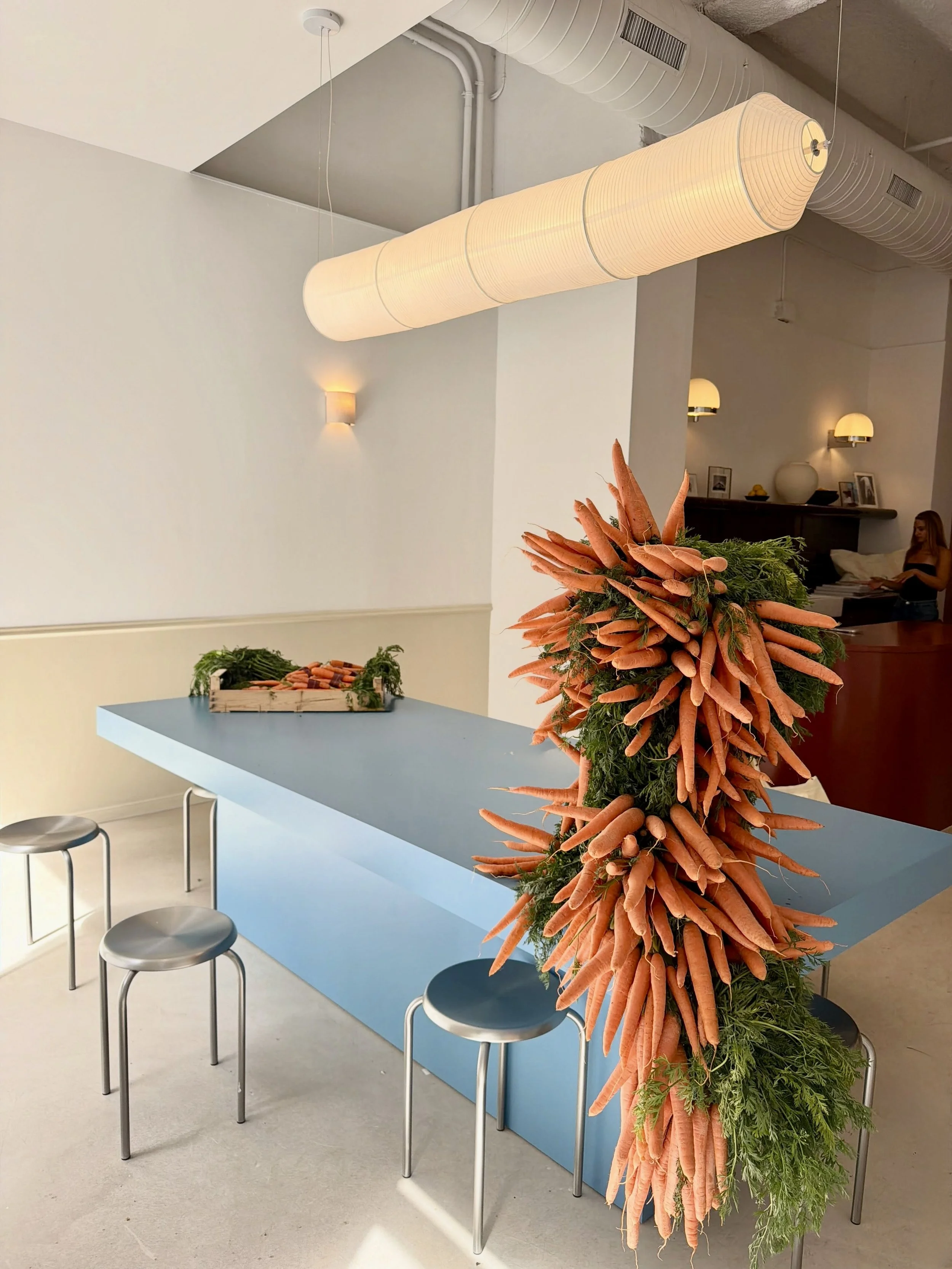 A bold botanical sculpture created by Mosaic for the Pranarôm press event, using fresh carrots and foliage to create a sculptural installation that brings the brand’s natural identity into the event space