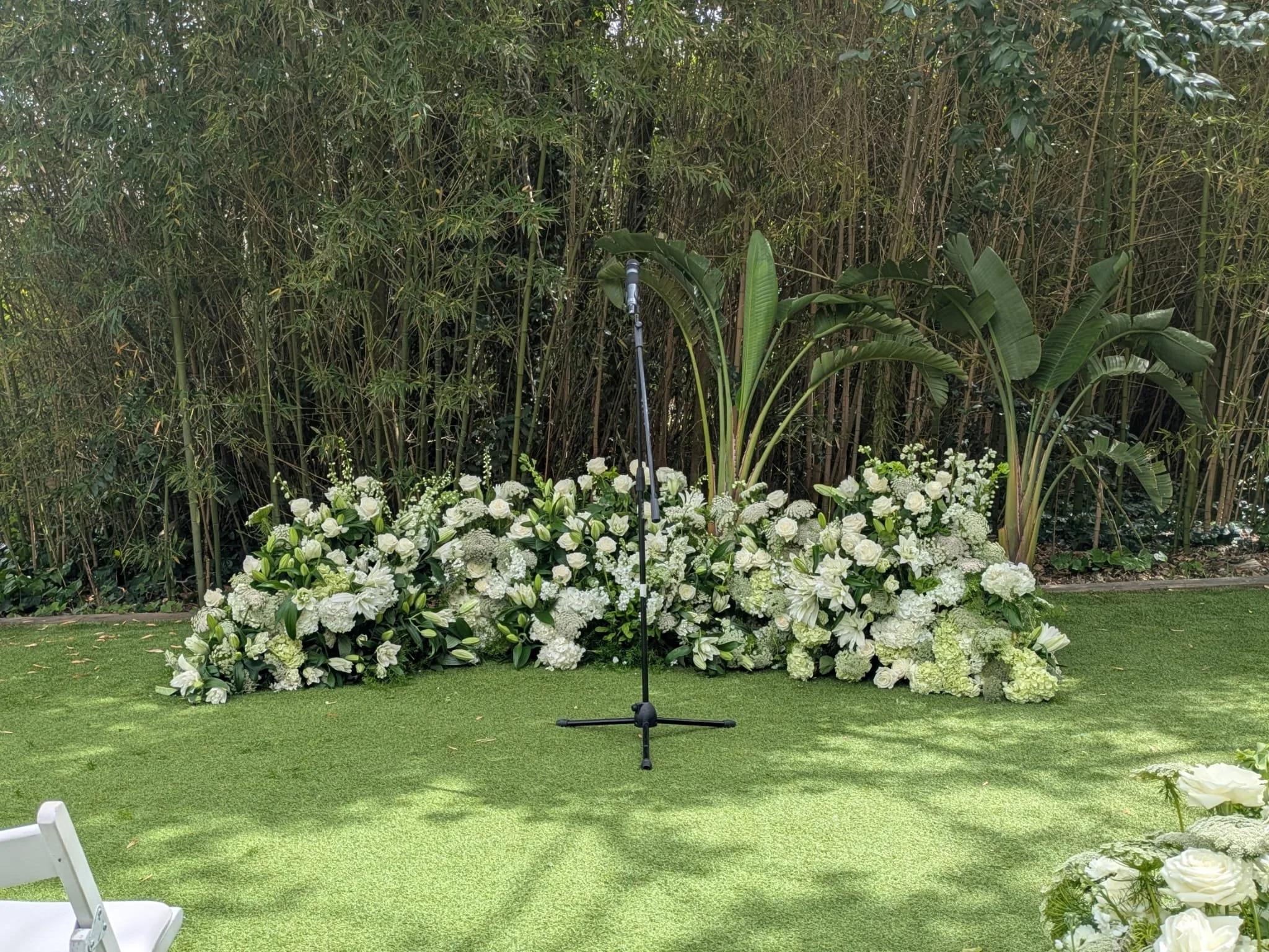 Luxury ceremony backdrop with abundant white flowers framing Christie and Andrew's outdoor wedding ceremony at Villa Almanita in Catalunya