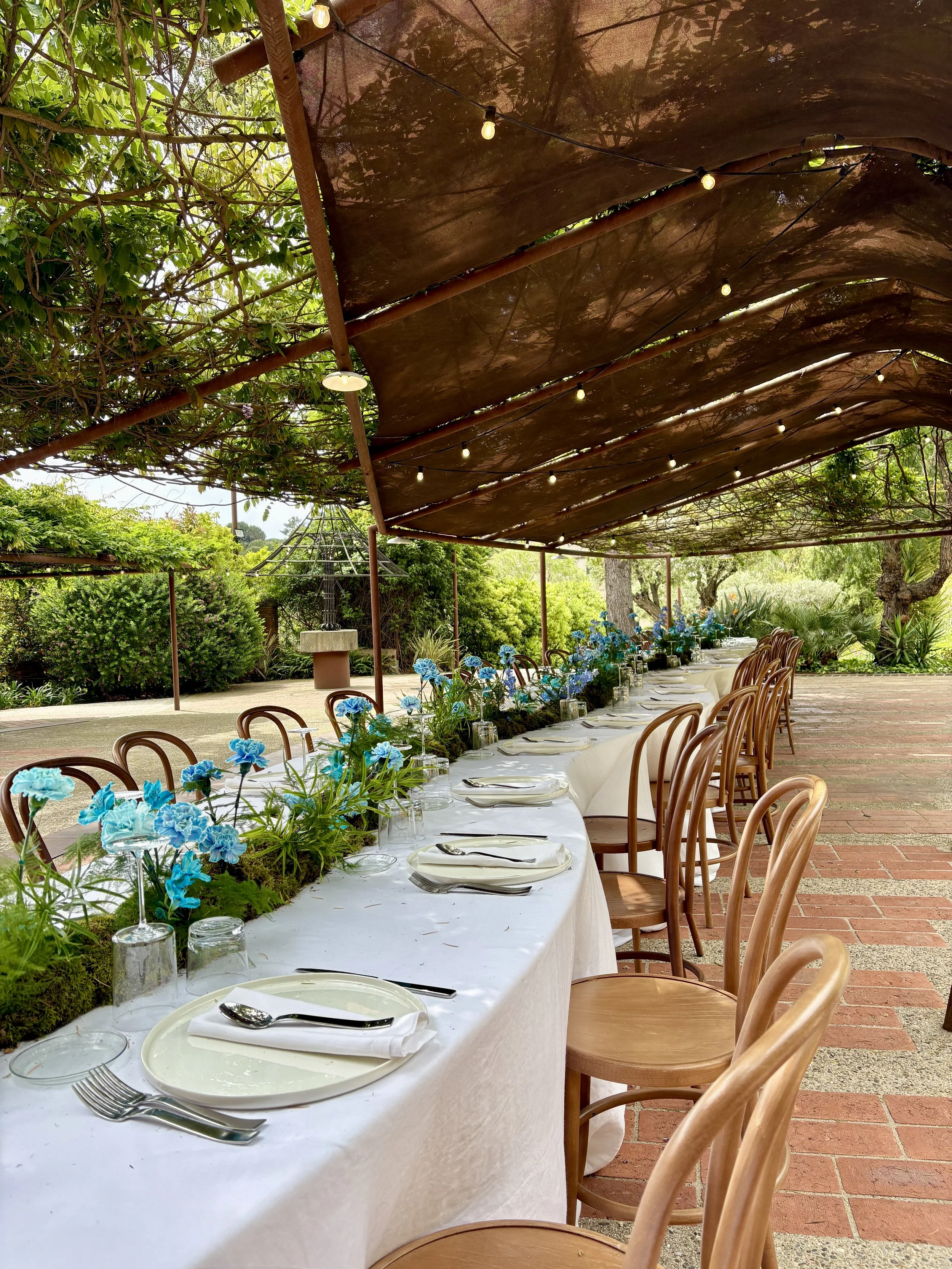 Bespoke 16-metre floral table runner created for the ASICS event organized by Gabsfood, featuring sculptural moss and vibrant blue flowers in a luxury masia near Barcelona