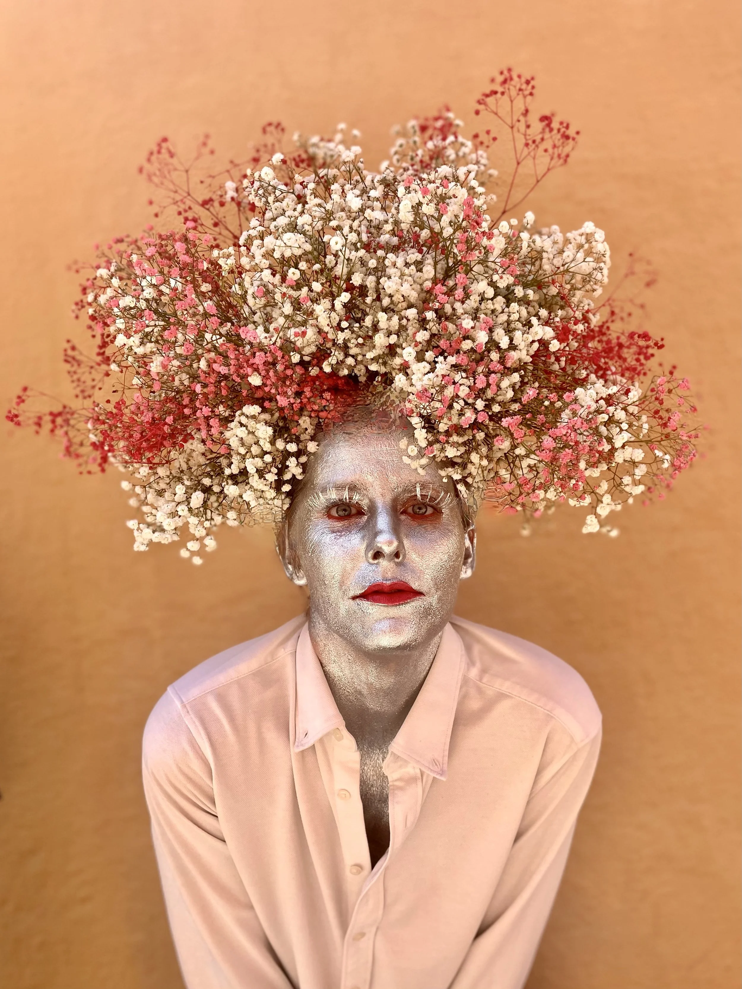 Side profile of Margaux as a cosmic goddess, wearing a fresh floral crown with silver-painted skin