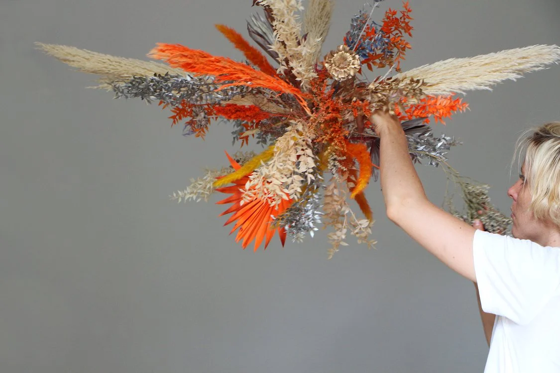 Floral artist Margaux of Mosaic hand-painting a suspended floral installation in warm tones for a luxury project in Barcelona