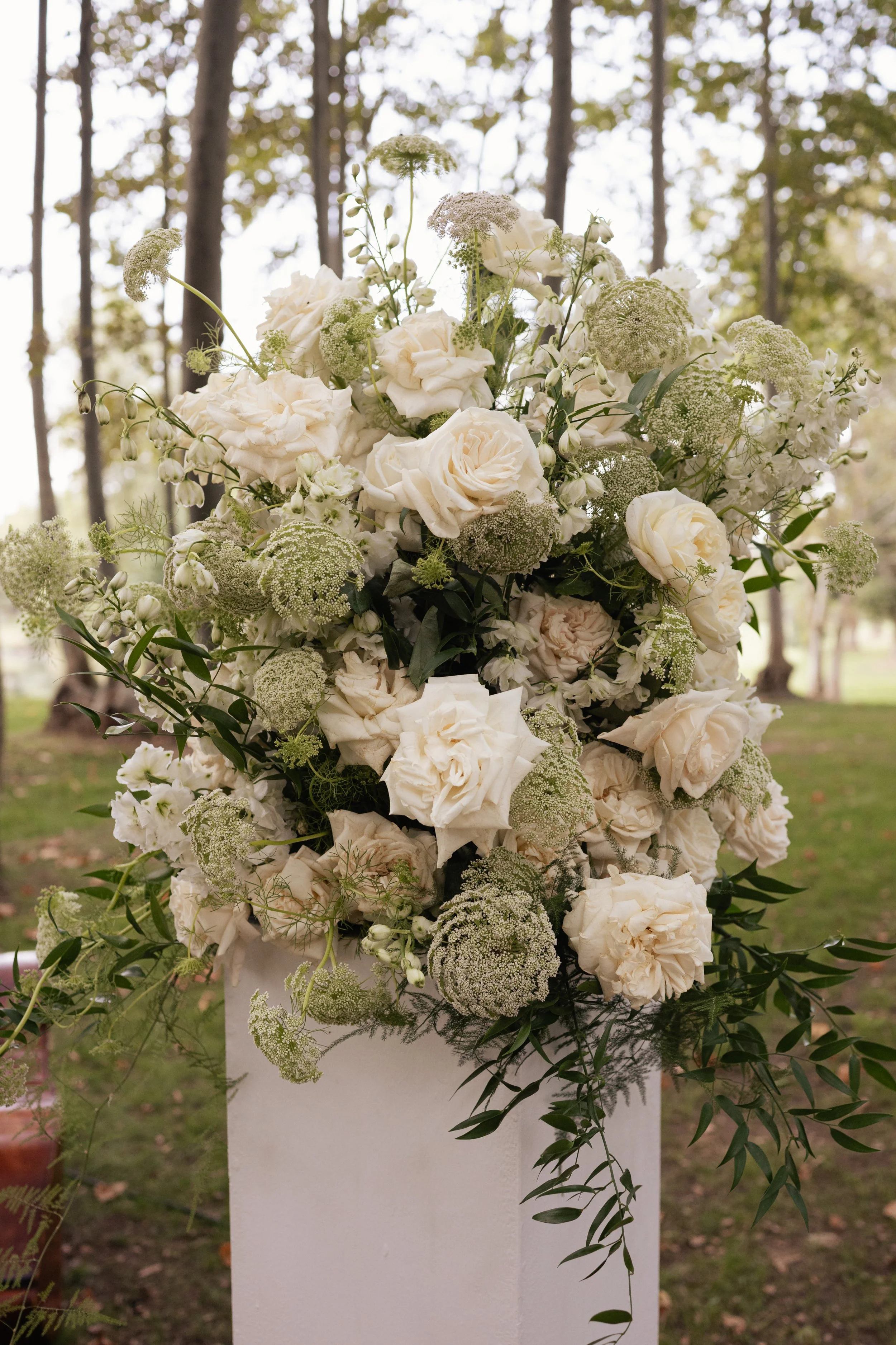 Lush white floral arrangement by Mosaic combining roses and seasonal blooms, created for a timeless and elevated wedding design
