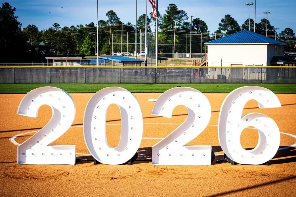 Large illuminated numbers displaying 2026 on a baseball field at sunset.