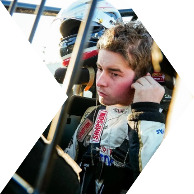 Race car driver wearing a racing suit and adjusting his helmet.
