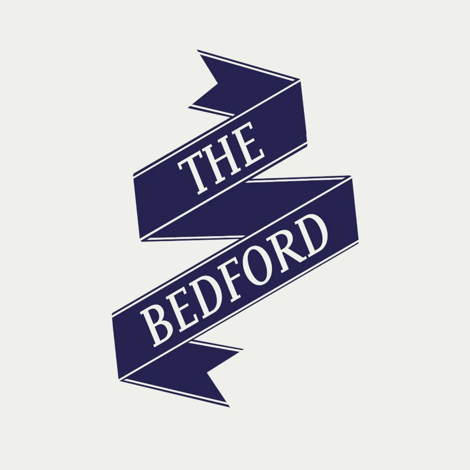 A dark blue ribbon banner with white outline text reading "The Bedford" on a light background.