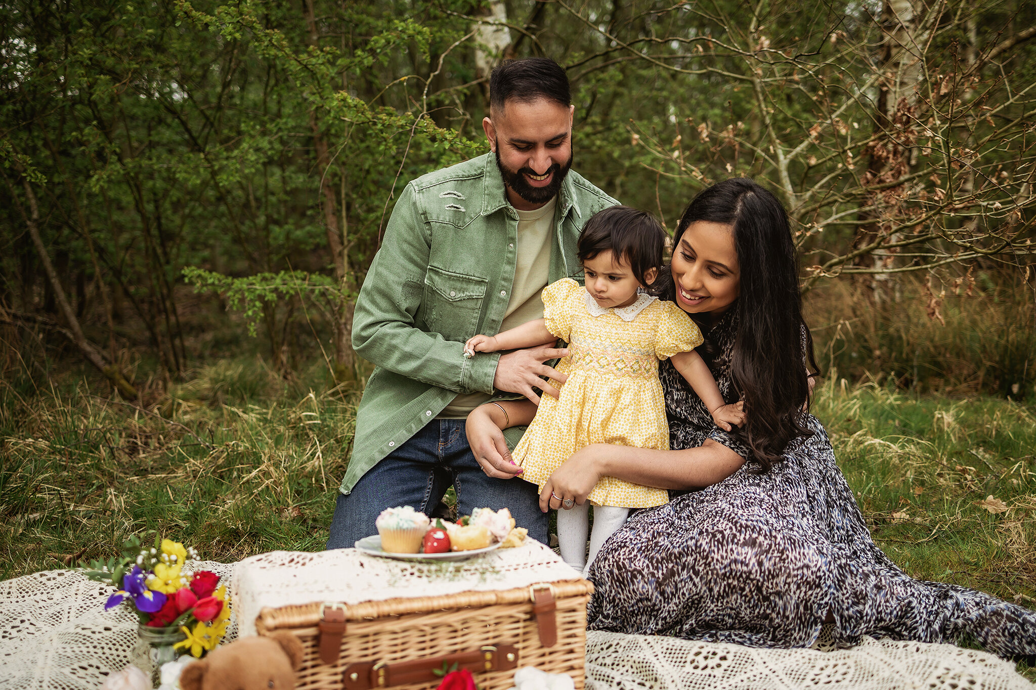 Mum and Dad join in with one year old little girl during an outdoor cake smash session in Derby