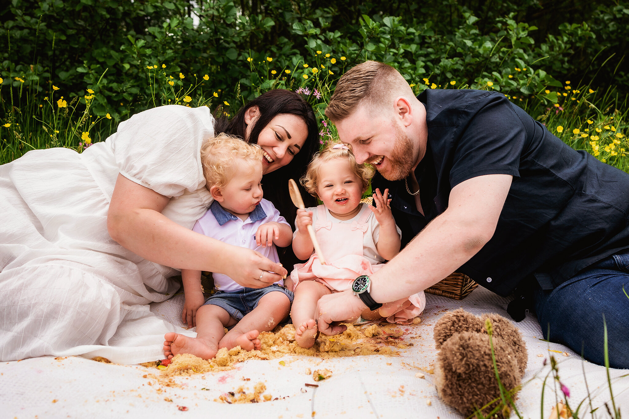 Mum and Dad join in with one year old twins during an outdoor cake smash session in Derby