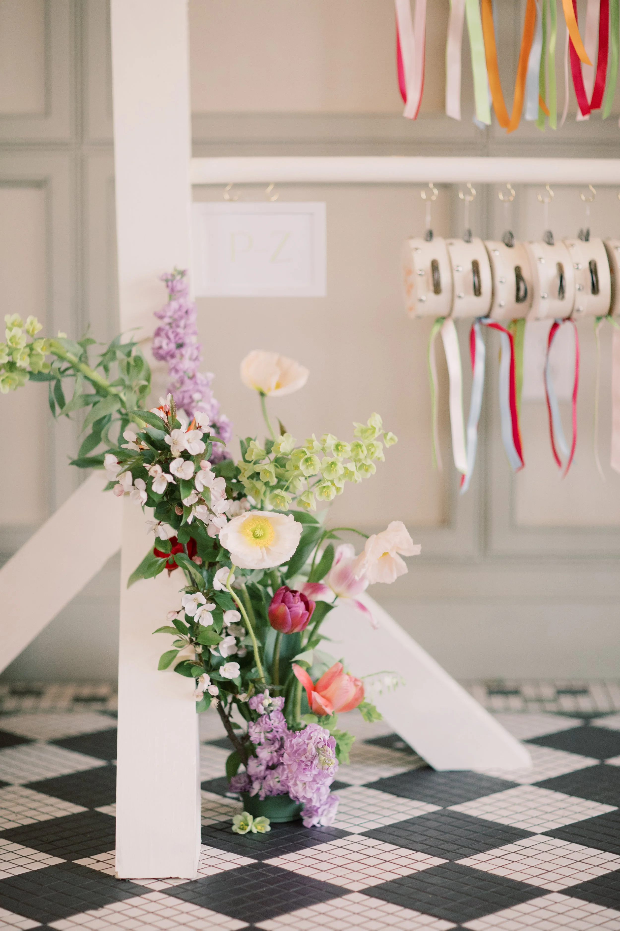 A colorful floral arrangement with pink, purple, and white flowers on a black and white checkered table.