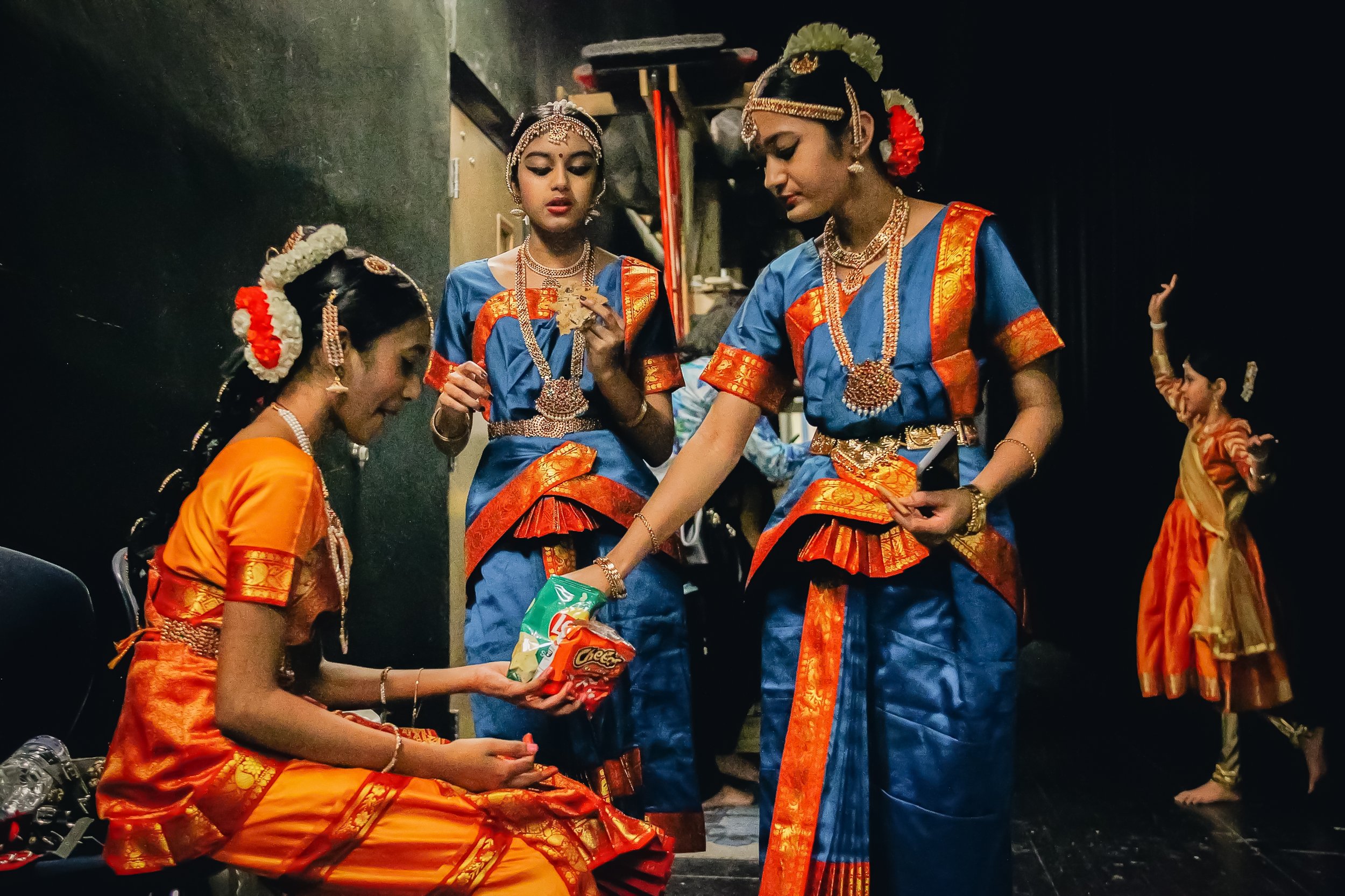 Students from the Soorya Performing Arts School eat snacks before taking to the stage during a traditional Kalyani dance festival at Battle High School on April 10, 2022 in Columbia, Mo. 