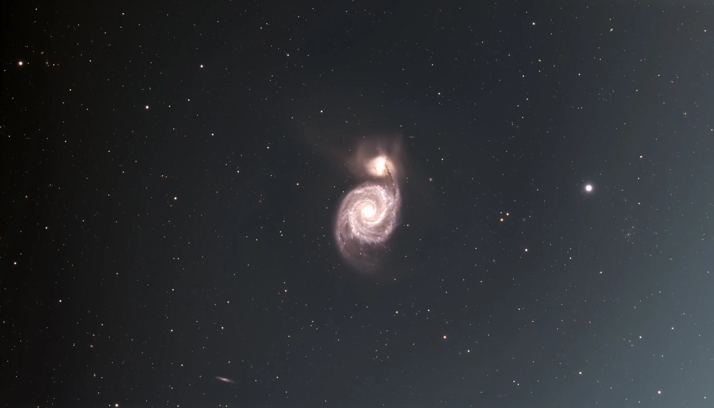 A galaxy with a bright core and spiral arms surrounded by numerous stars in the background.