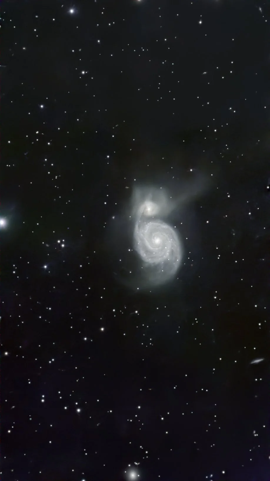 An image of a galaxy captured in deep space with numerous stars scattered across the dark background, featuring a prominent spiral galaxy at the center.