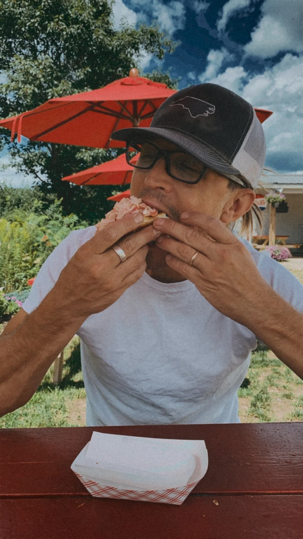 Sean eating a Cindy's lobster roll at a picnic table