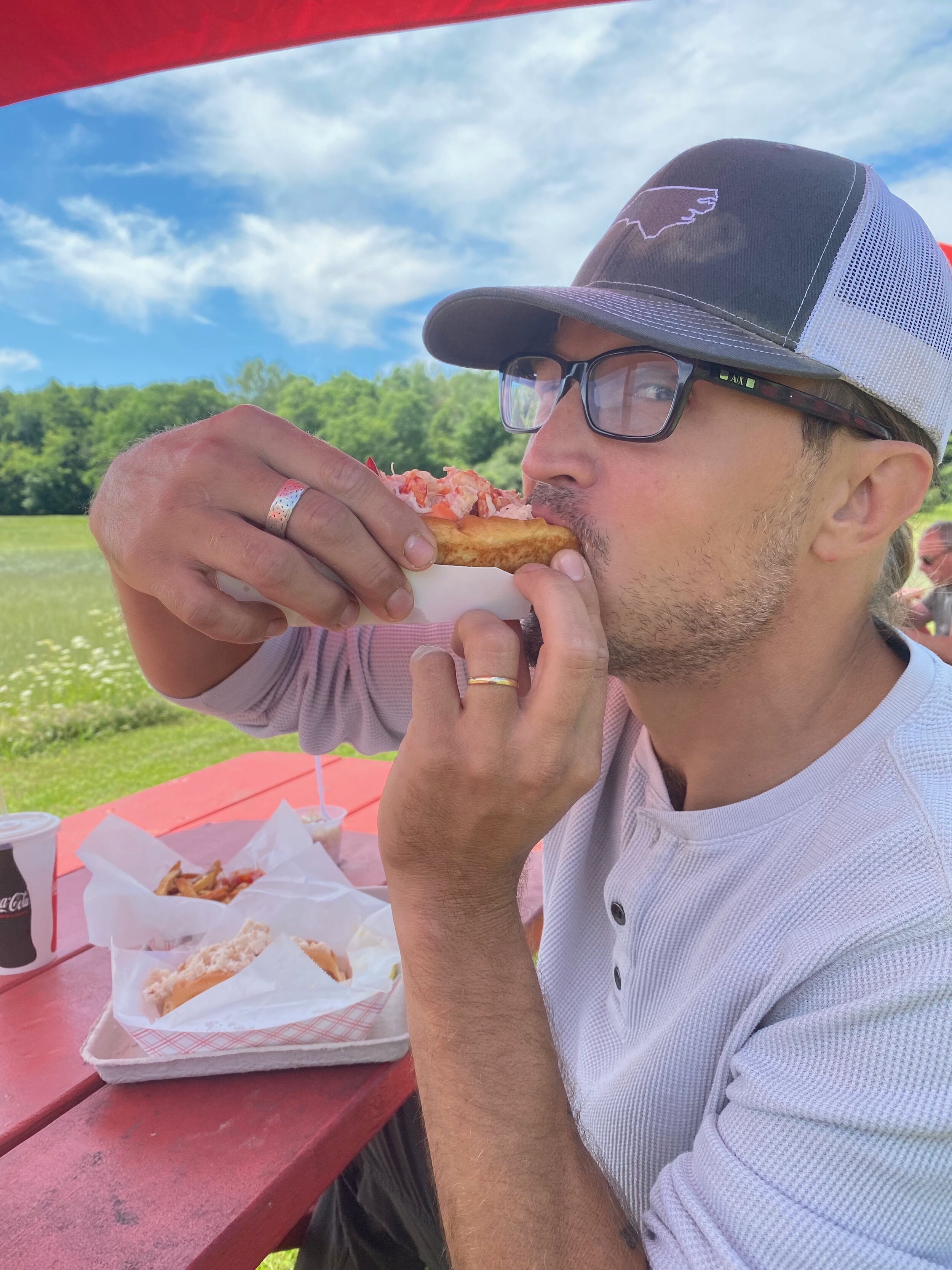 Sean eating a Day's lobster roll sitting at a picnic table