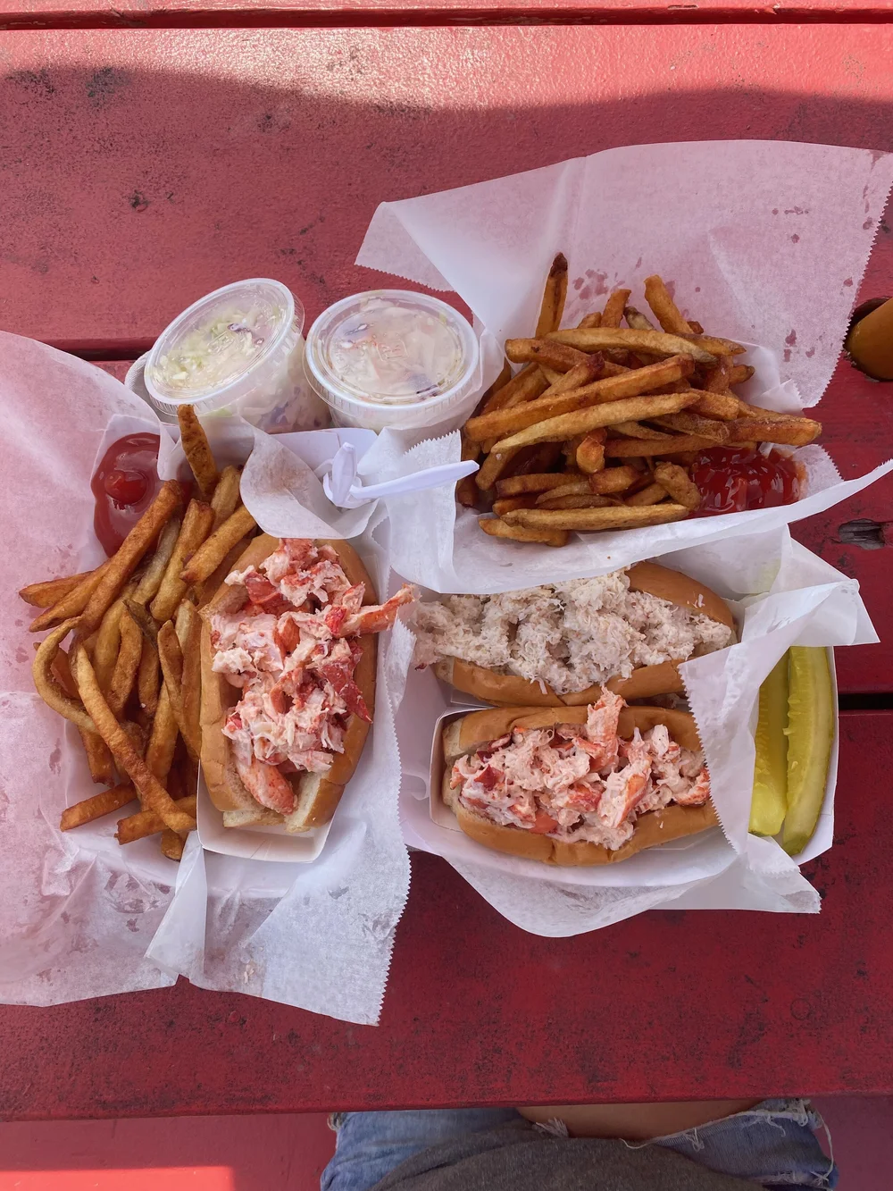 Day's lobster rolls with french fries, ketchup, coleslaw and pickles on a tray
