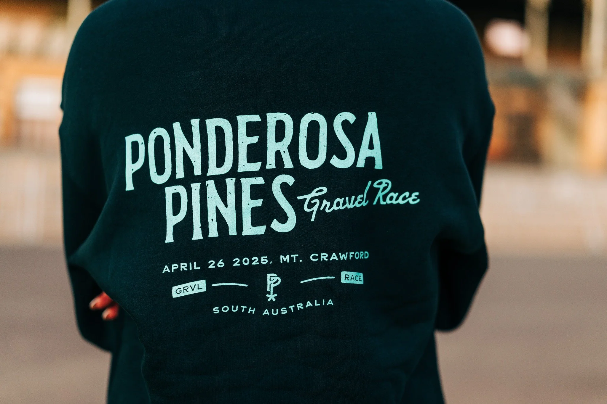 Back of a person wearing a black hoodie with white and teal text promoting the Ponderosa Pines Travel Race event on April 26, 2025, at Mount Crawford, South Australia.