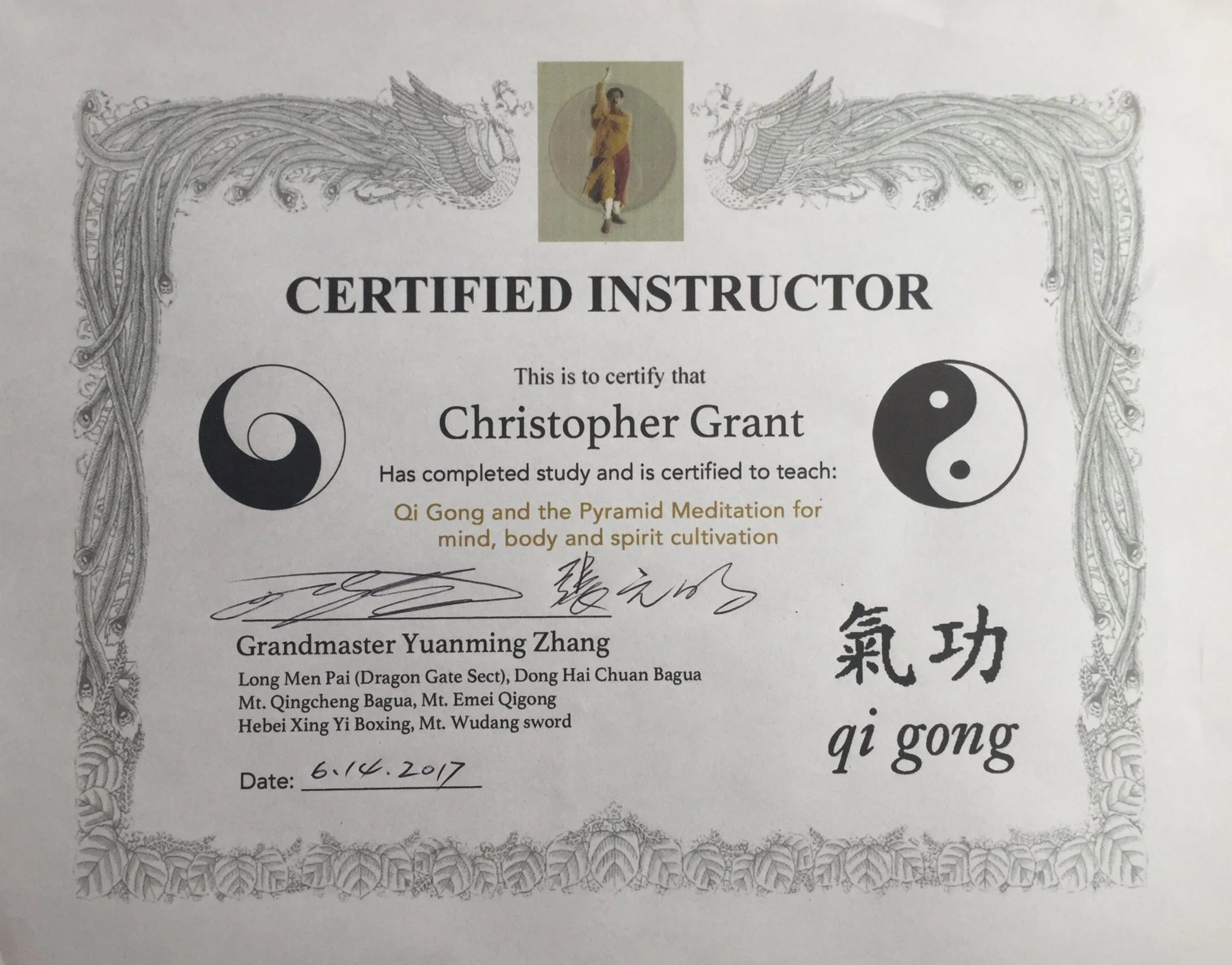 Certificate of achievement for Christopher Grant, certified instructor in Qi Gong and pyramid meditation, signed by Grandmaster Yuanming Zhang, dated June 14, 2017, with yin-yang symbols and Chinese characters.