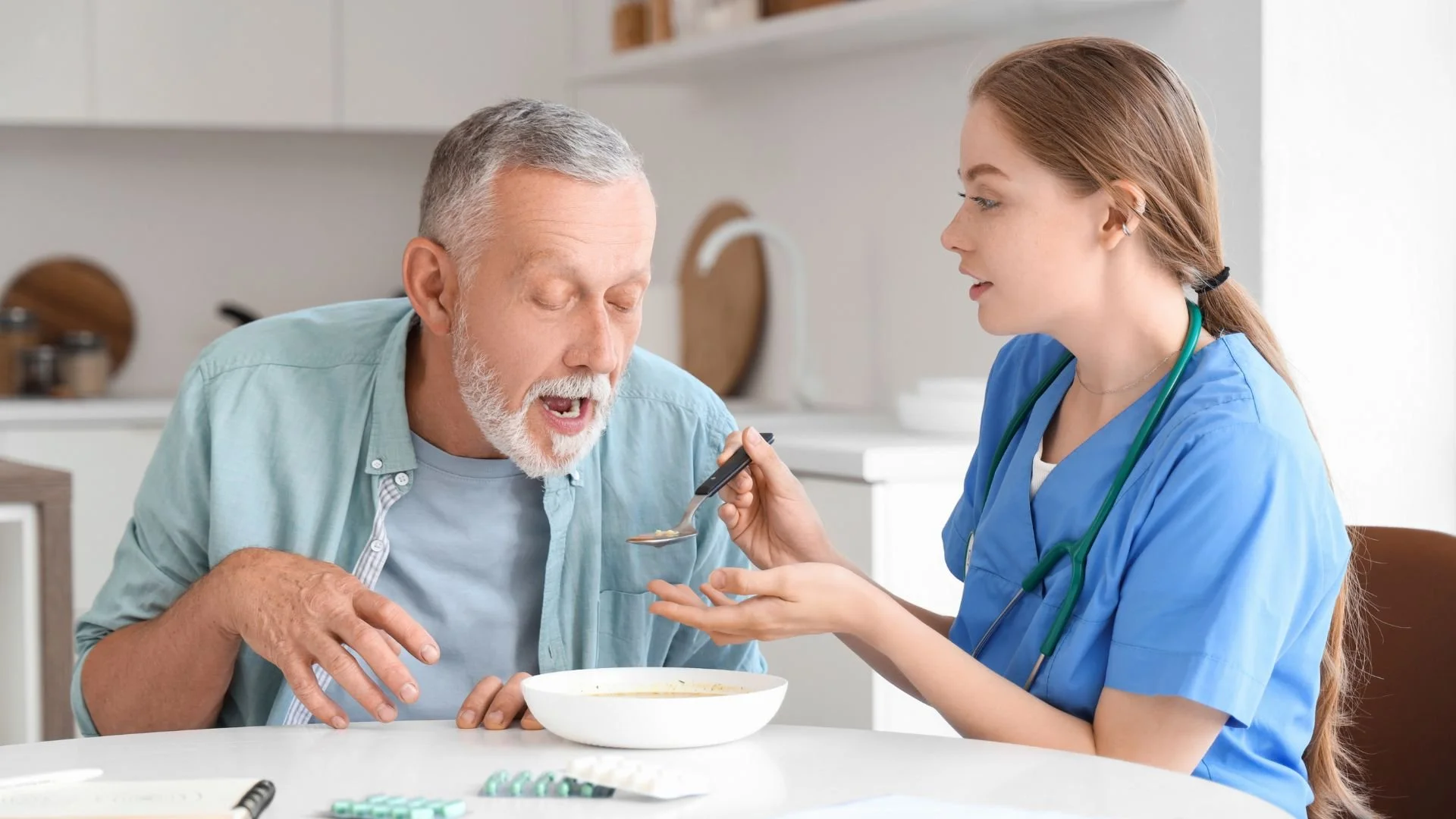 Caregiver feeds a man with Parkinson's disease