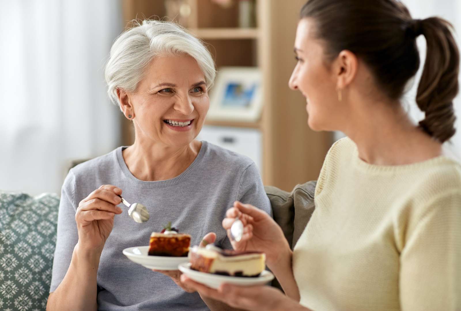 Old Mother and Adult Daughter Eating Cake at Home