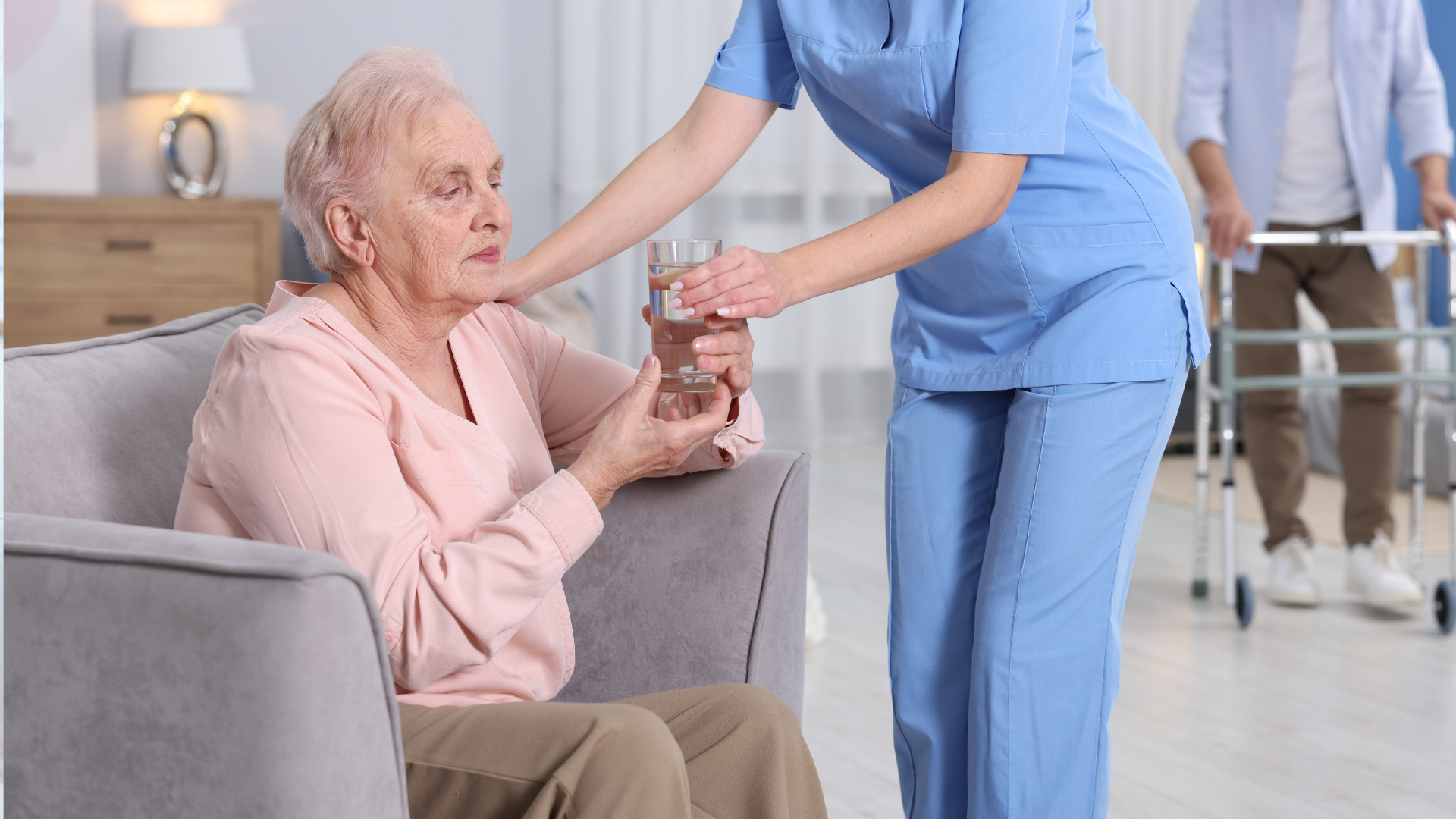 Care Worker Giving Glass of Water to Senior Woman at Retirement Home, Closeup
