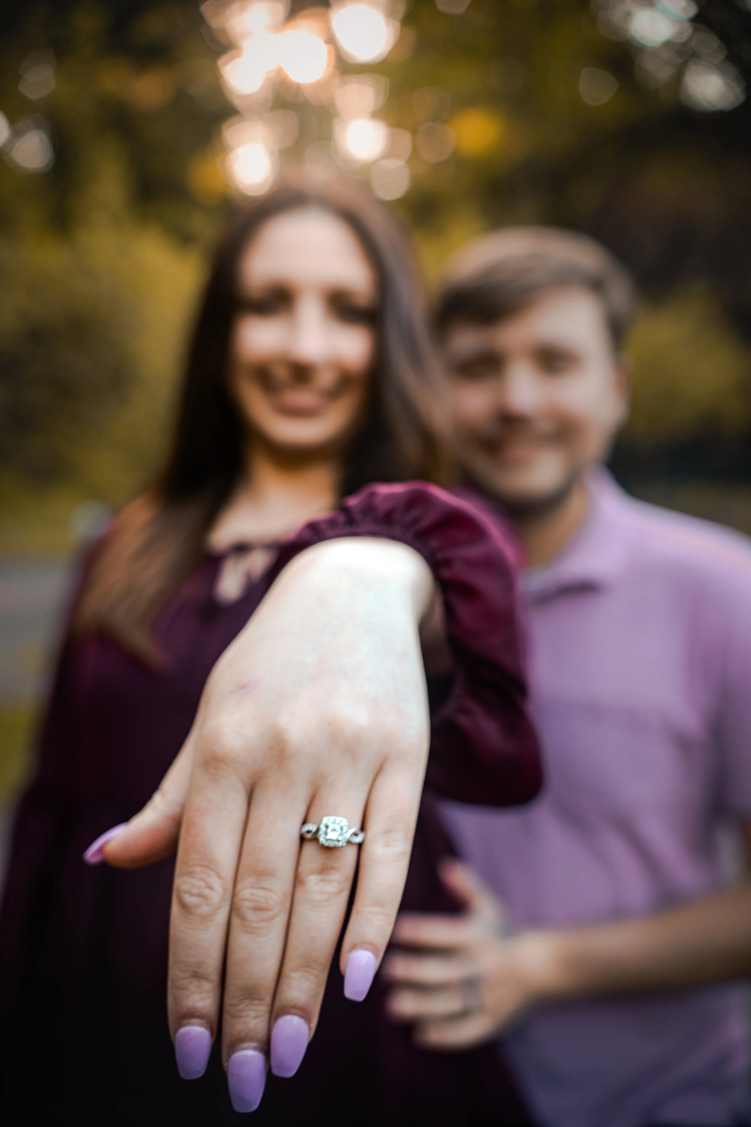 Couple with woman showing engagement ring, focus on hand