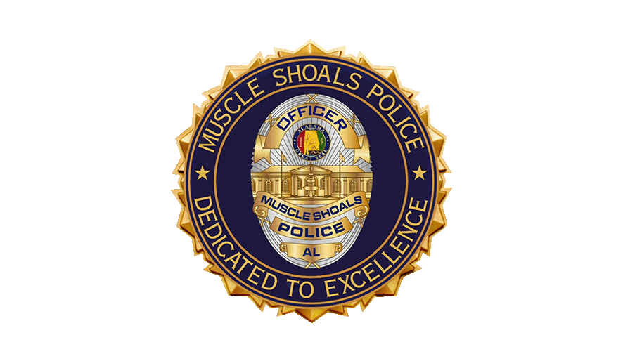 Badge of the Muscle Shoals Police Department featuring a circular design with gold, black, and blue colors, displaying the department's emblem and the motto 'Dedicated to Excellence'.