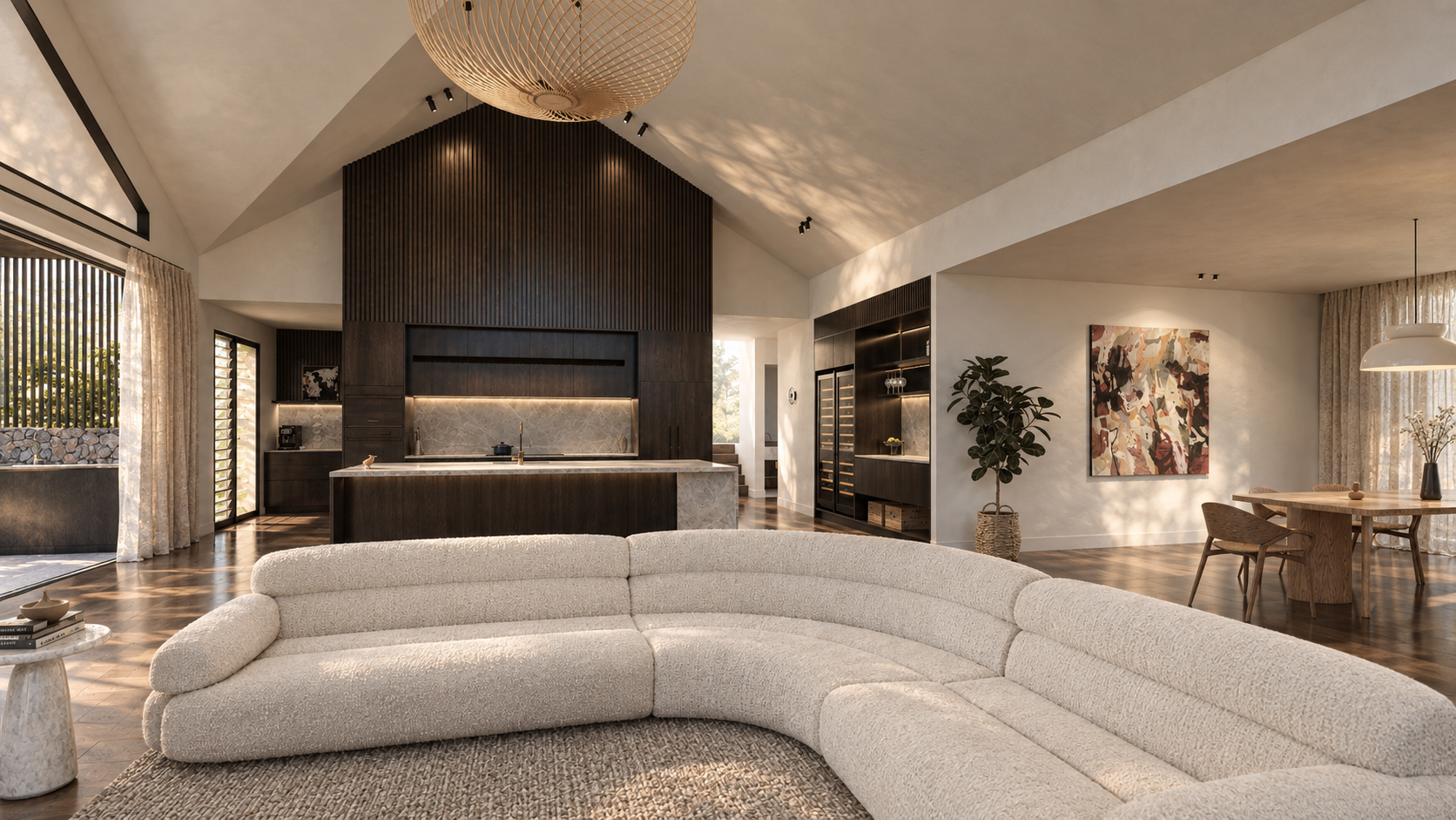 Modern open-concept living room with curved cream sectional sofa, dark wood kitchen island, dining area, and pendant lighting