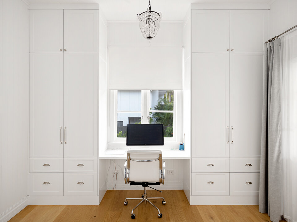 A home office with plenty of storage and a view to the outside, complete with a chandelier.