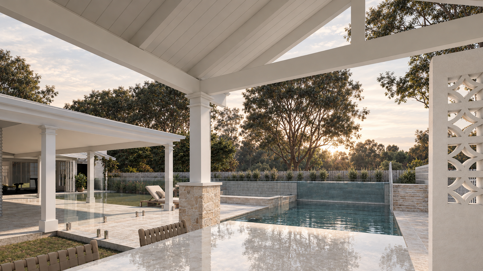 A backyard featuring a swimming pool, a shaded patio area, and outdoor furniture, with trees and a fence in the background at sunset.