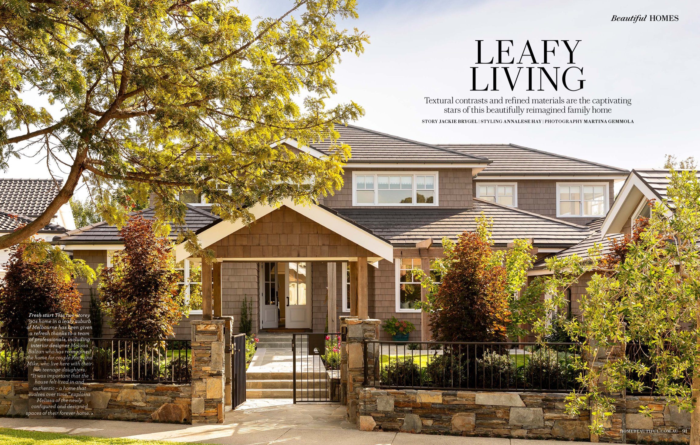 A two-story family home in a leafy suburb of Melbourne, with a dark tiled roof, brown exterior siding, a white front door, and a small front yard with trees, shrubs, and a stone fence.