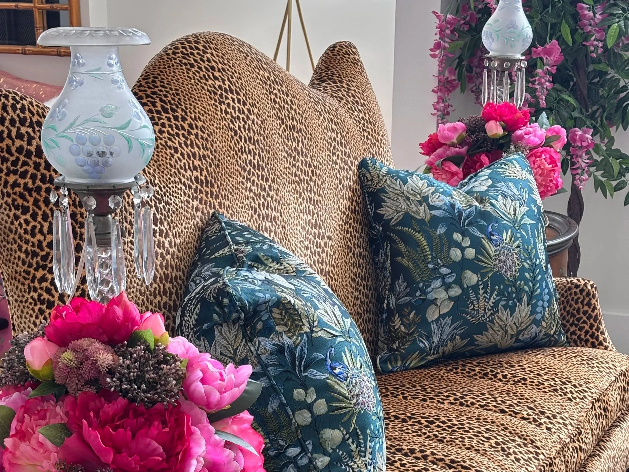 Lepard print couch with bold blue flower pillows.
